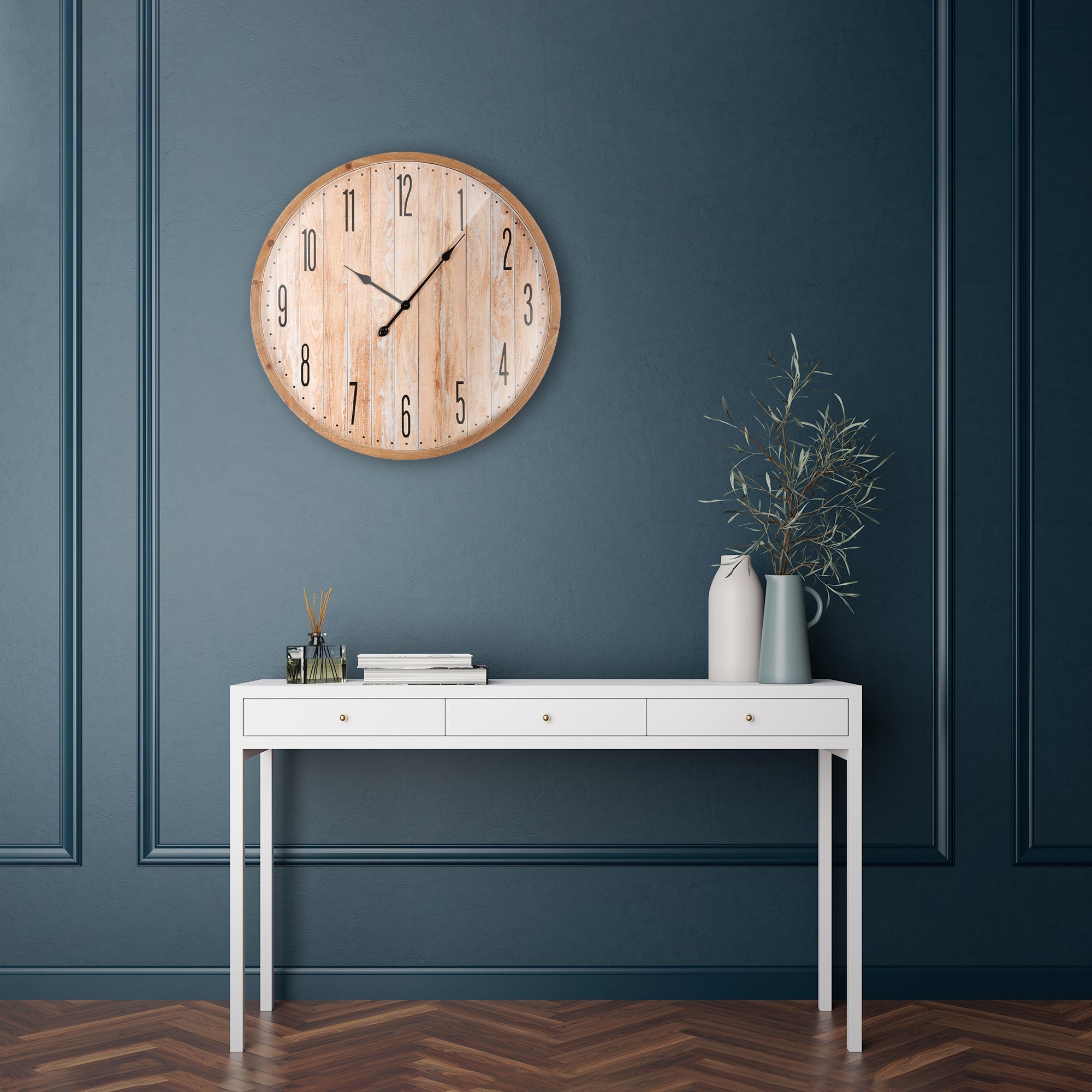 Holzuhren an einer blauen Wand über einem weißen Tisch mit Pflanzen und Büchern.