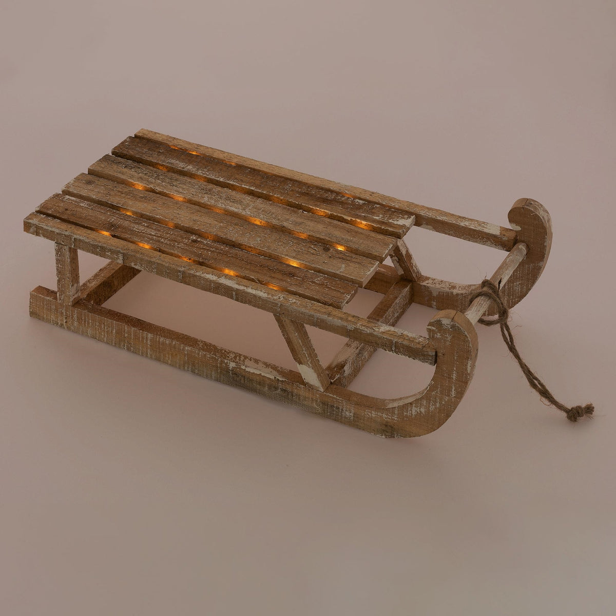 Holzschlitten mit Lichtern auf einem einfarbigen Hintergrund.