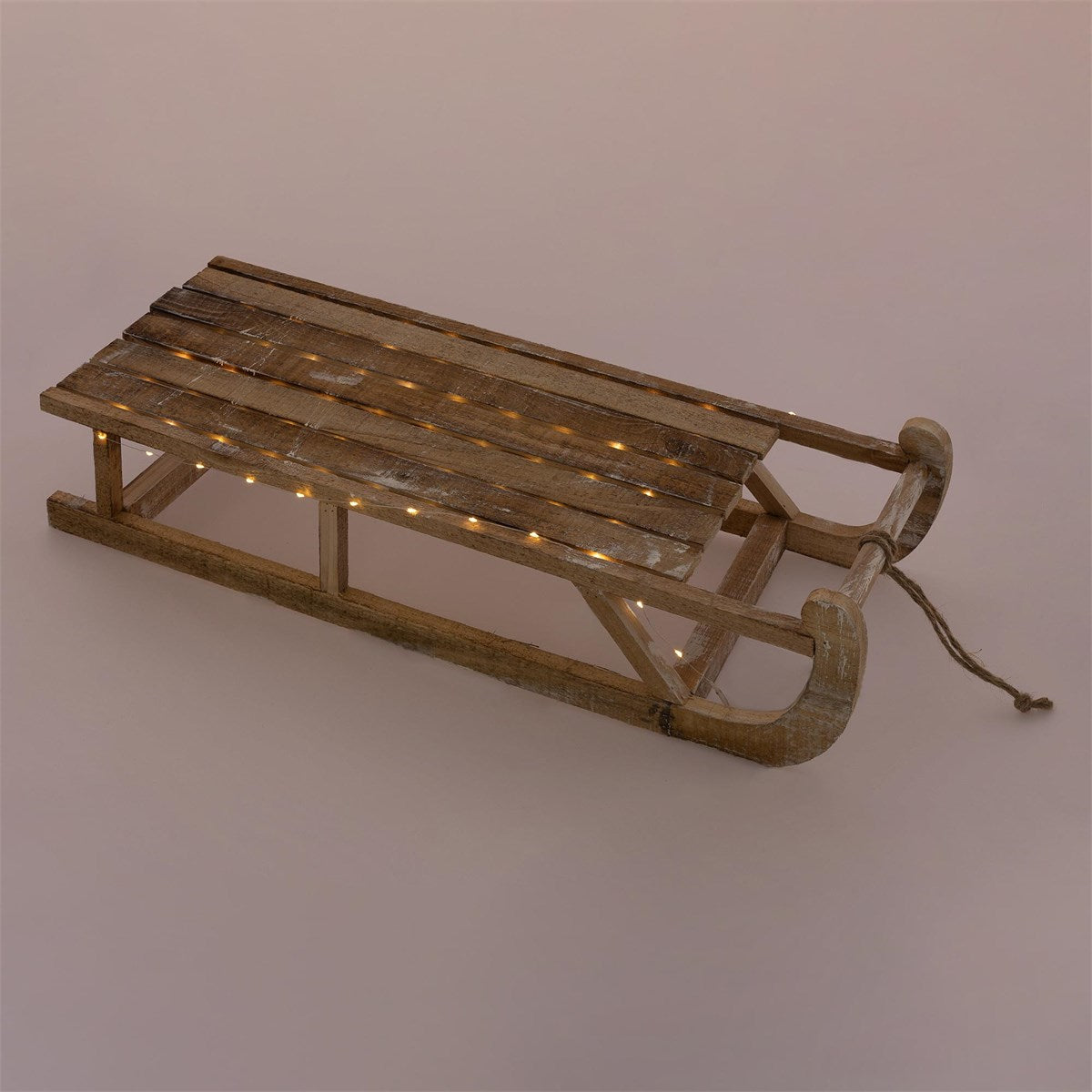 Un trineo rústico de madera con luces sobre una superficie neutra.