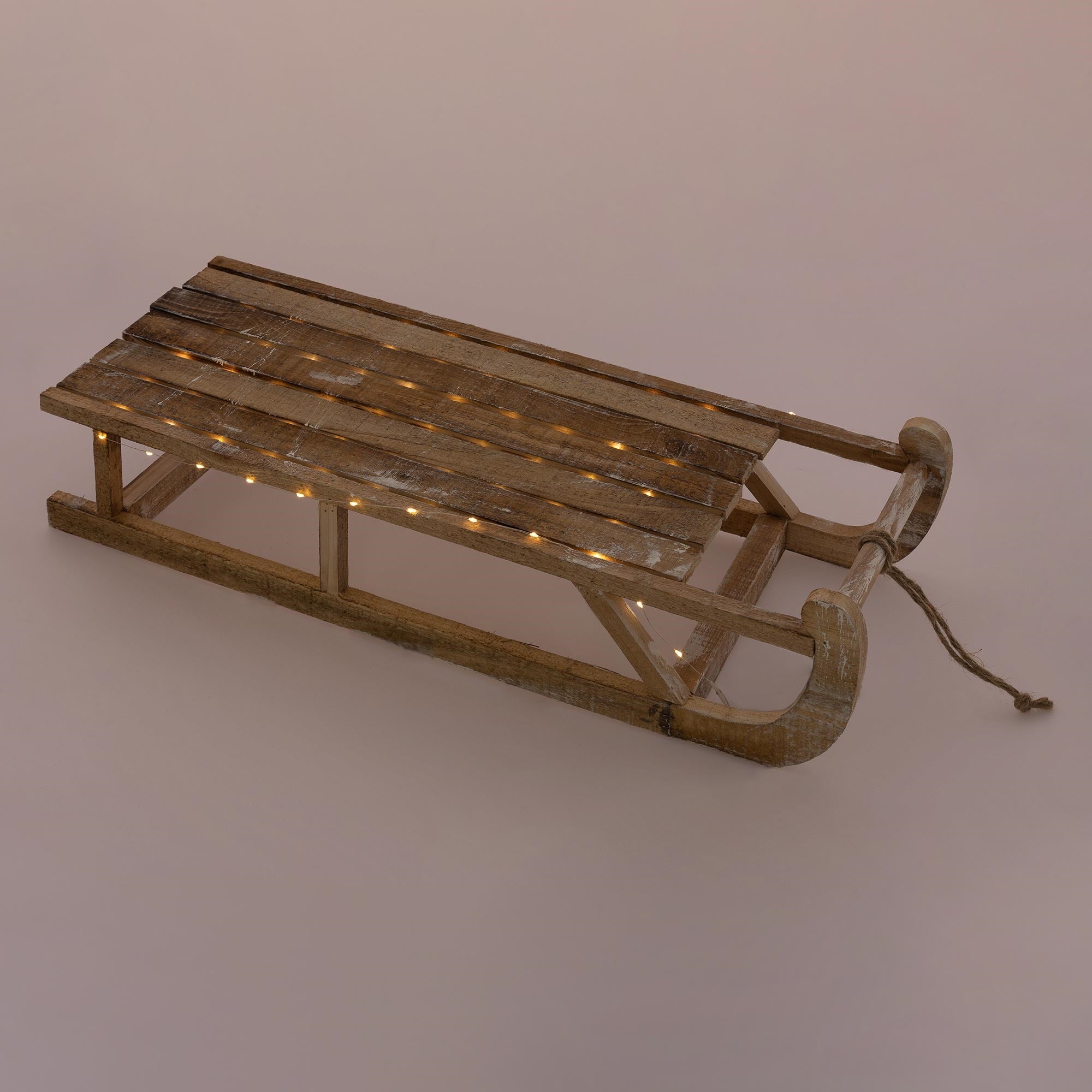 Une luge en bois rustique avec des lumières sur une surface neutre.