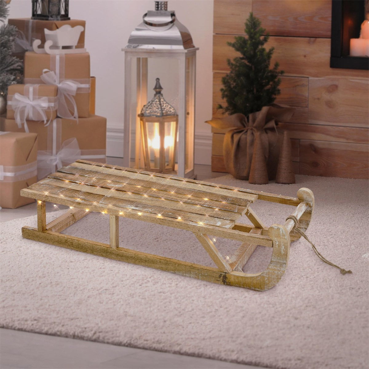 Trineo de madera con luces sobre una alfombra, delante de un fondo rústico.