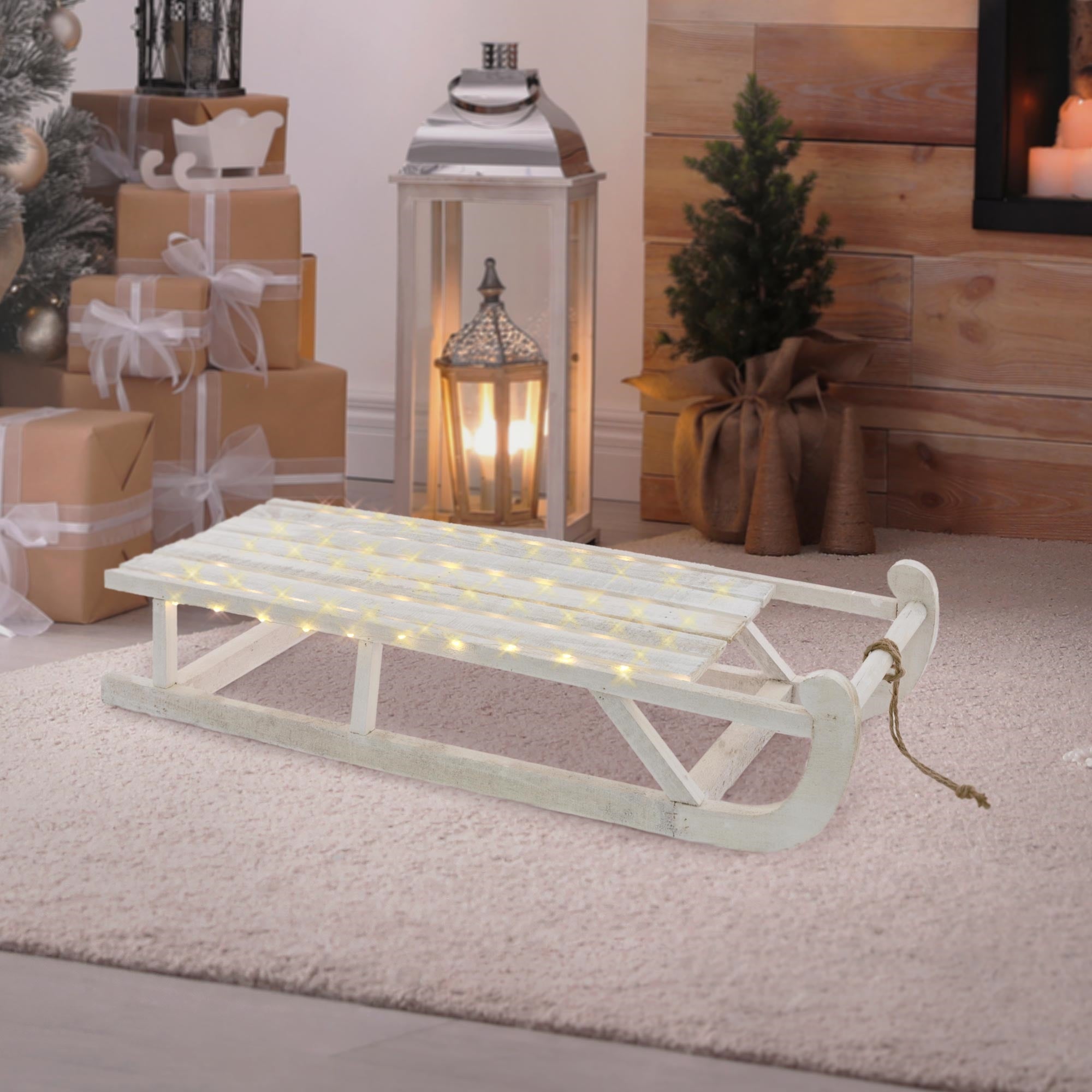 Luge blanche avec des lumières, sur un tapis dans une pièce avec des cadeaux.