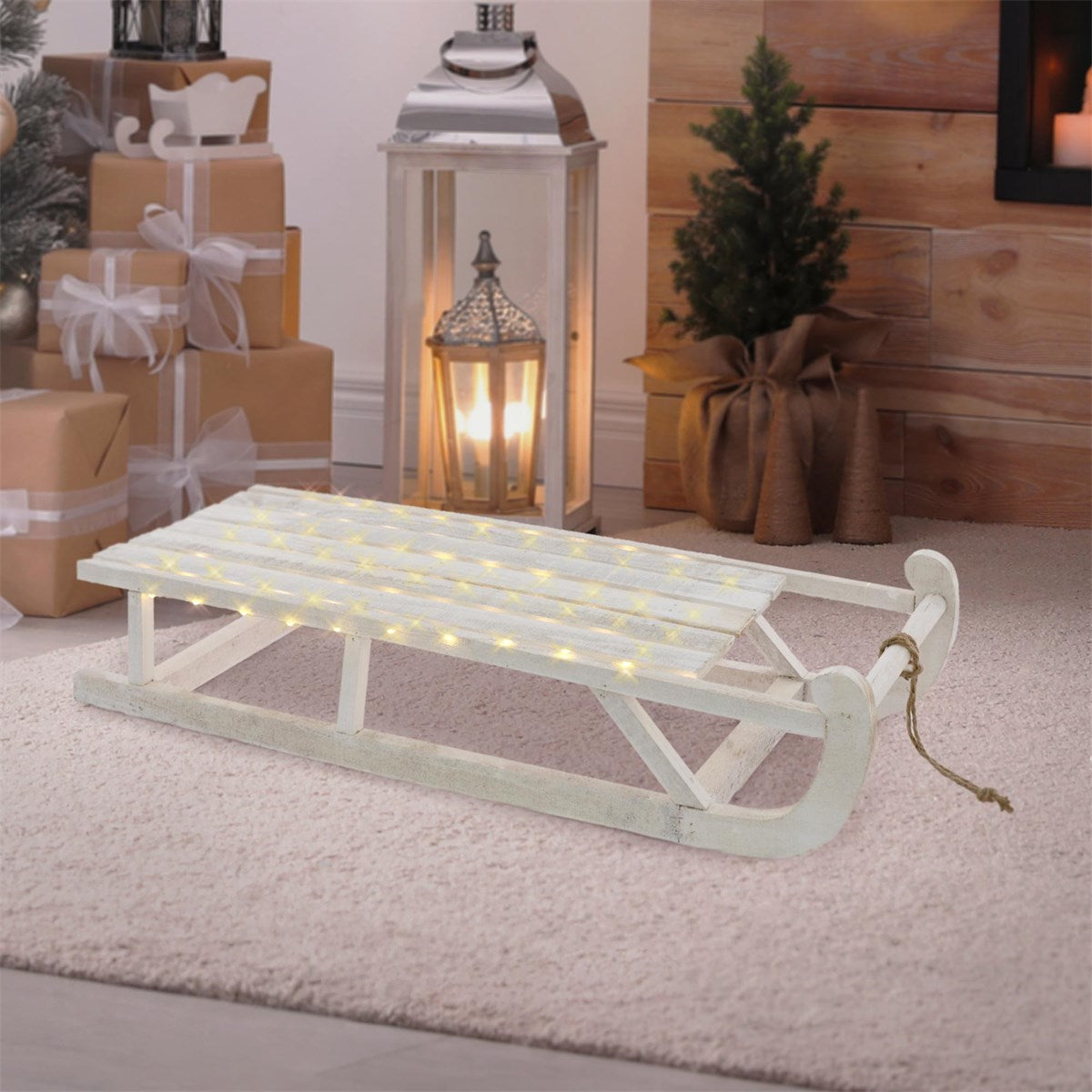 White sleigh with lights, surrounded by gifts and a lantern in a room.