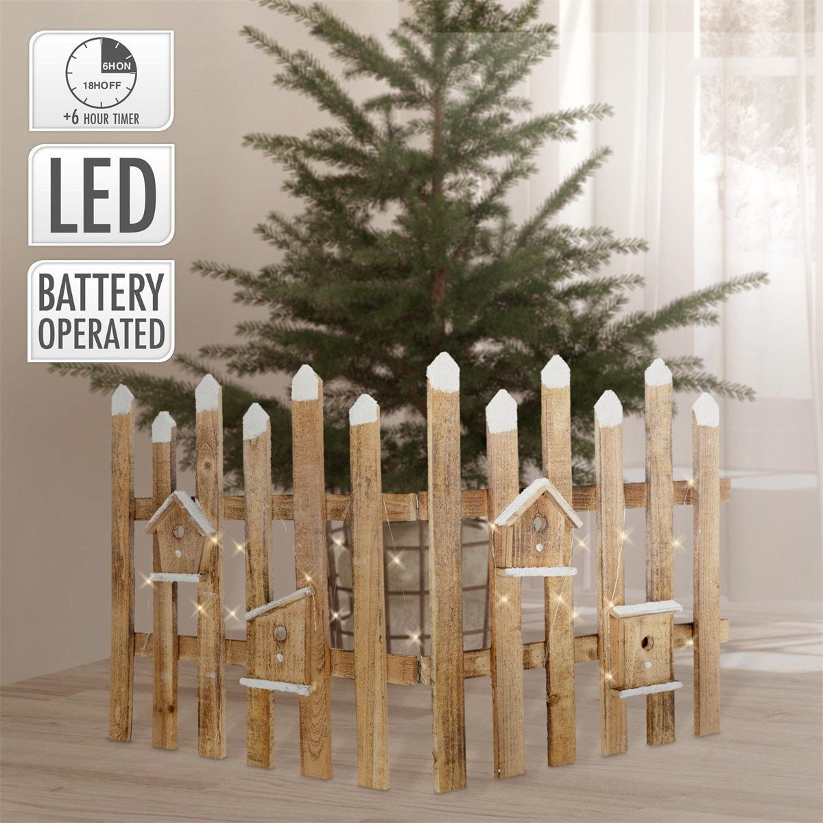 Ein rustikaler Zaun um einen Weihnachtsbaum mit Lichtern.