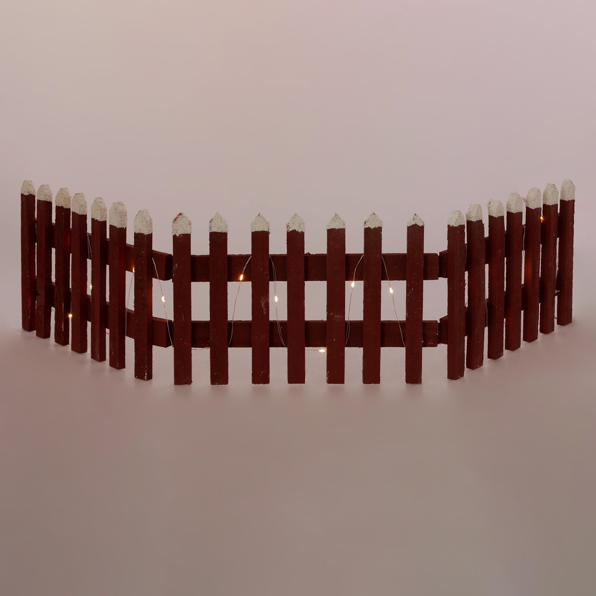 Valla de madera con puntas blancas y luces, en forma curvada.