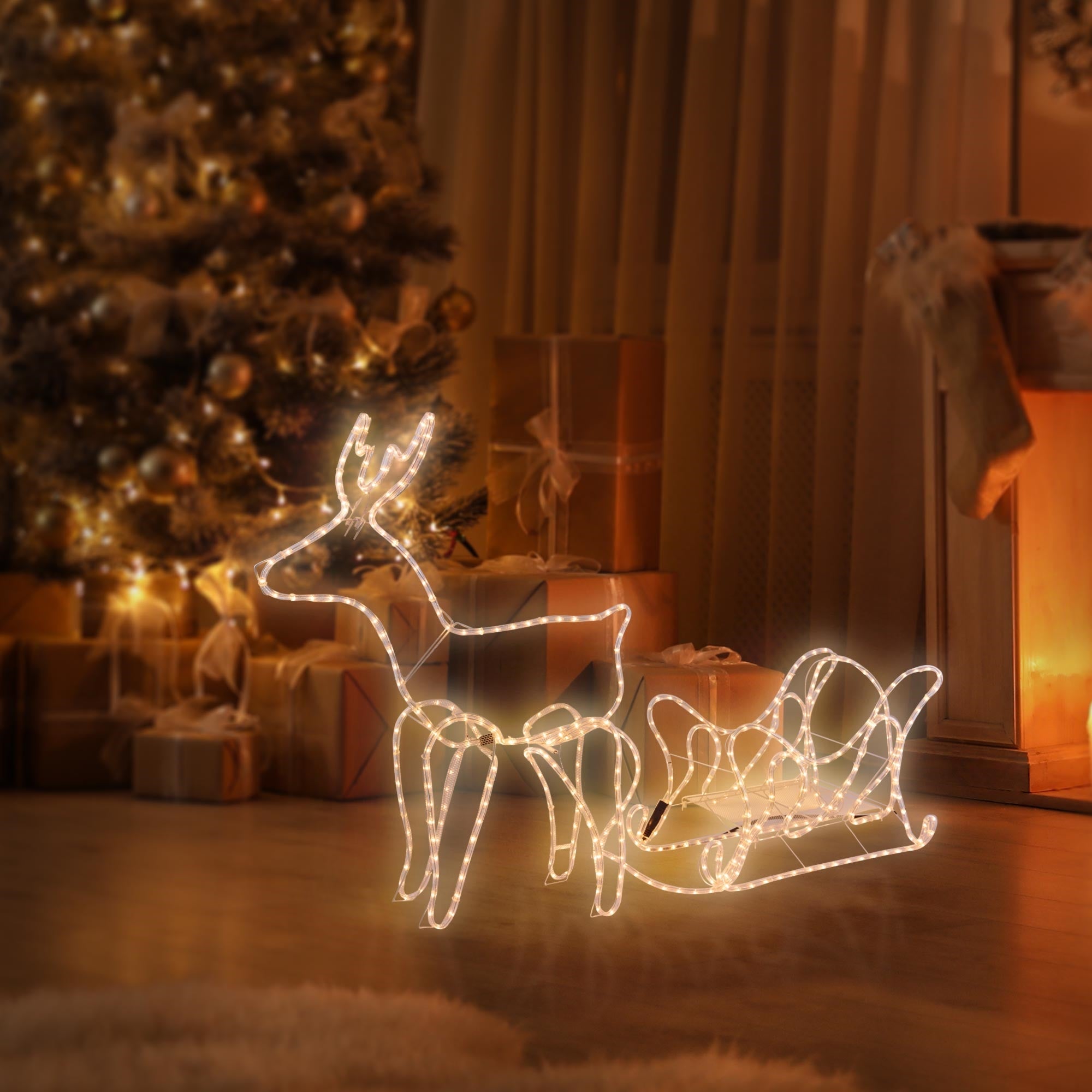 Beleuchtetes Rentier mit Schlitten vor einem Weihnachtsbaum.