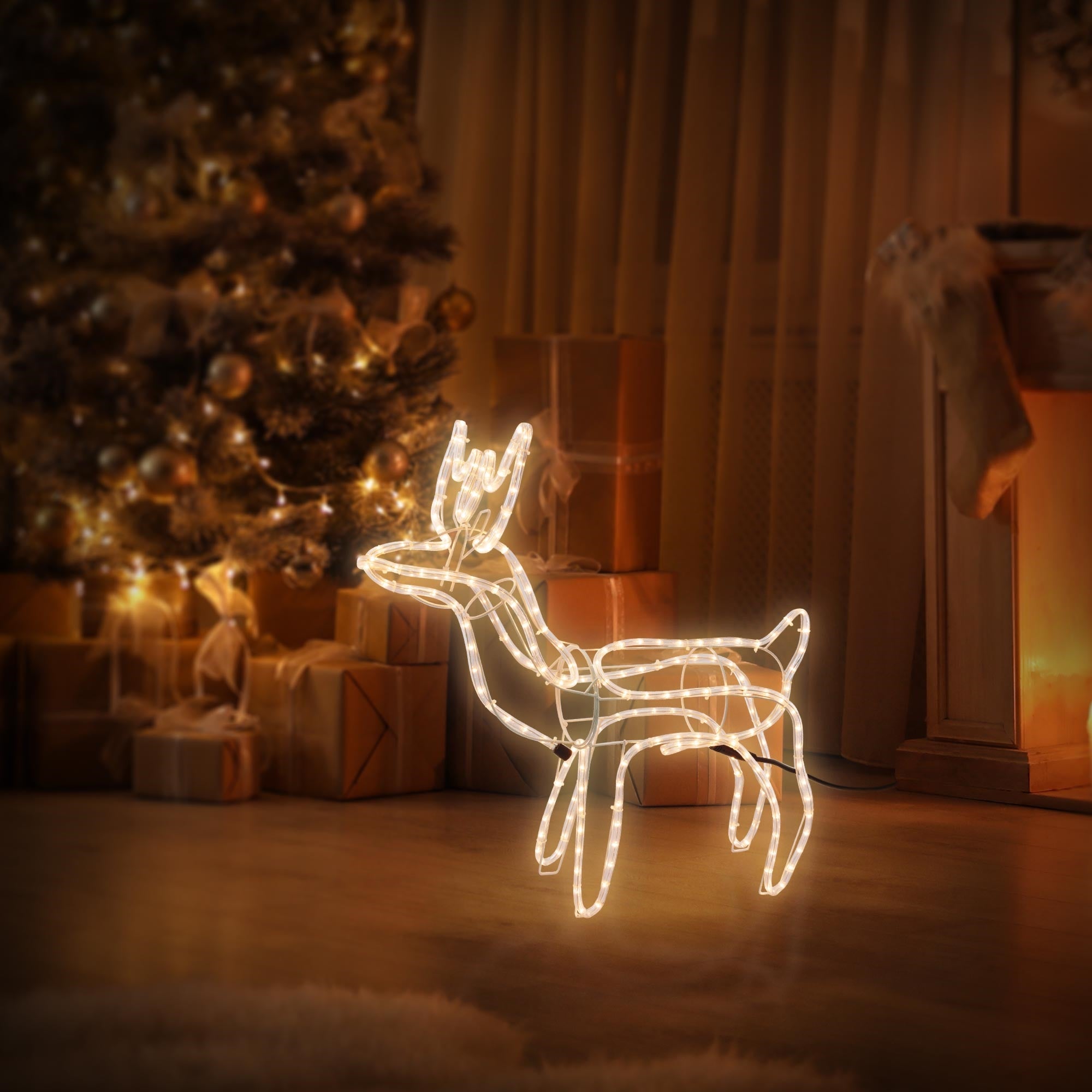 Leuchtendes Rentier aus Draht vor einem Weihnachtsbaum und Geschenken.