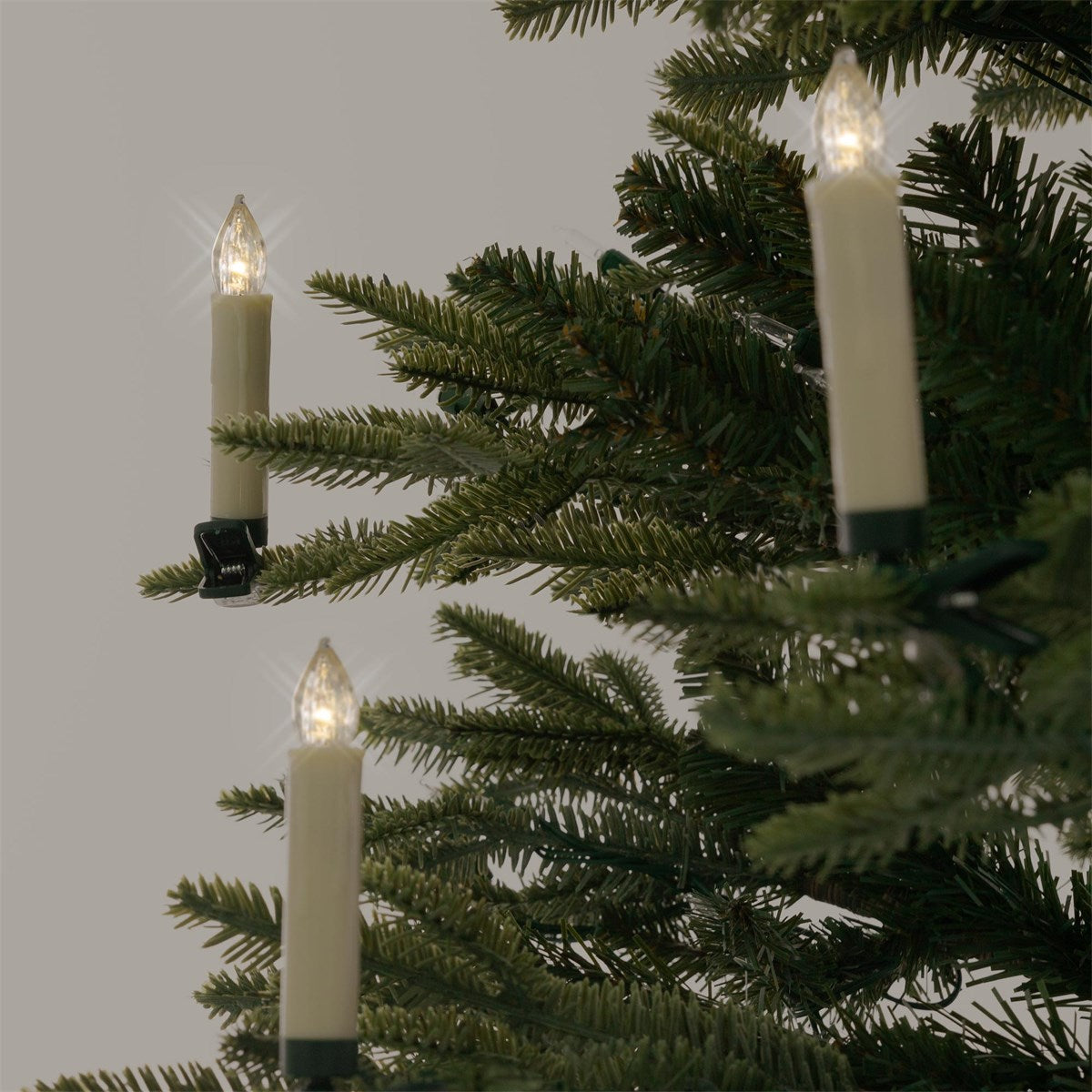Trois bougies allumées sur un sapin de Noël.
