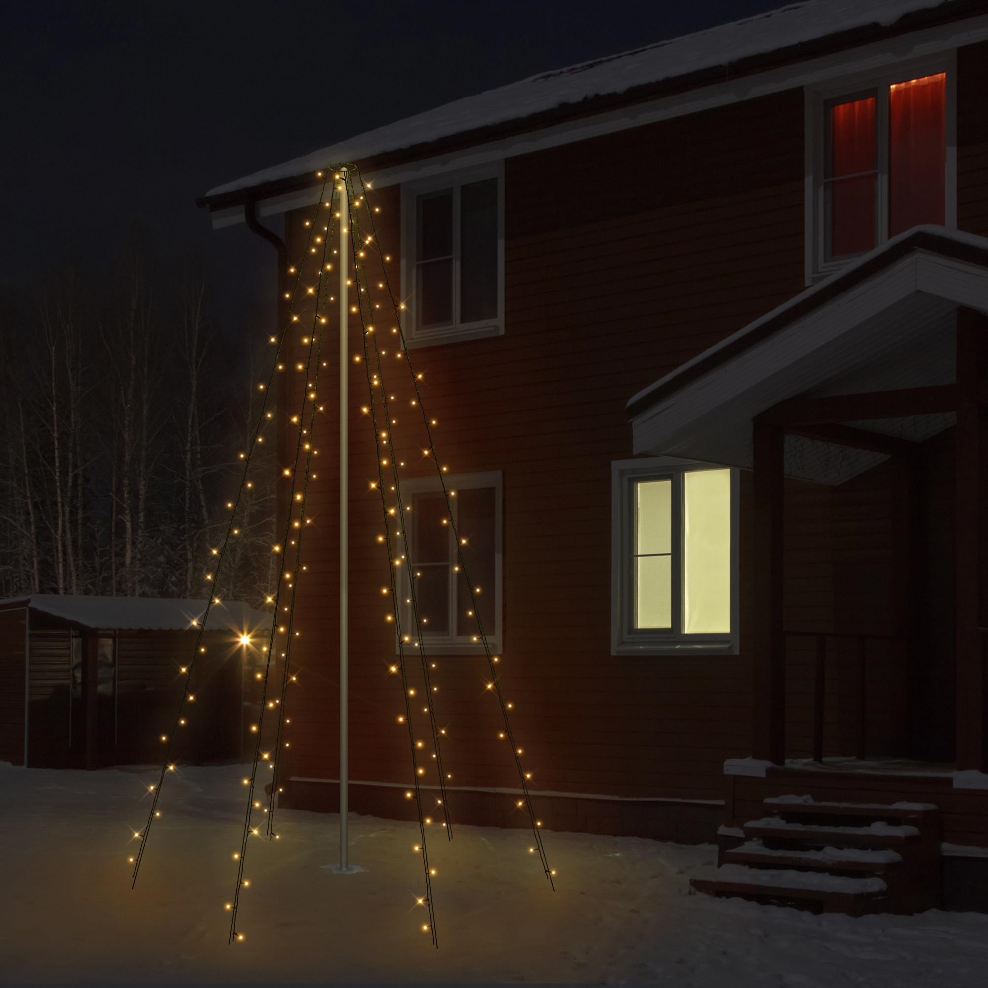Beleuchteter Weihnachtsbaum vor einem Holzhaus im Schnee bei Nacht.
