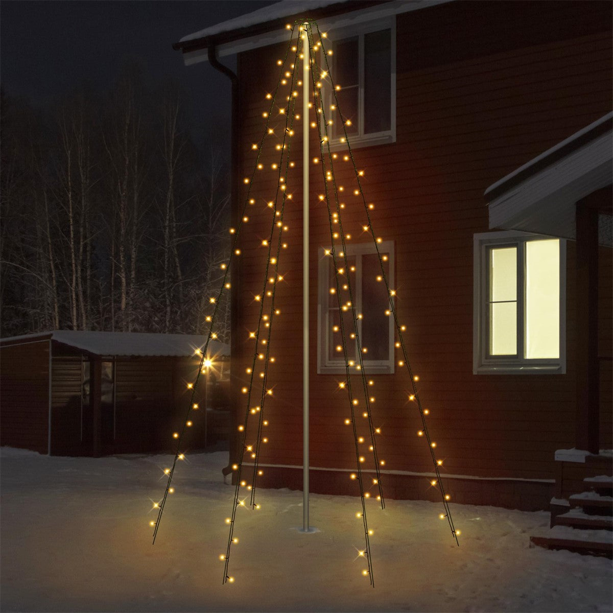 Beleuchteter Weihnachtsbaum vor einem Haus in der Nacht.