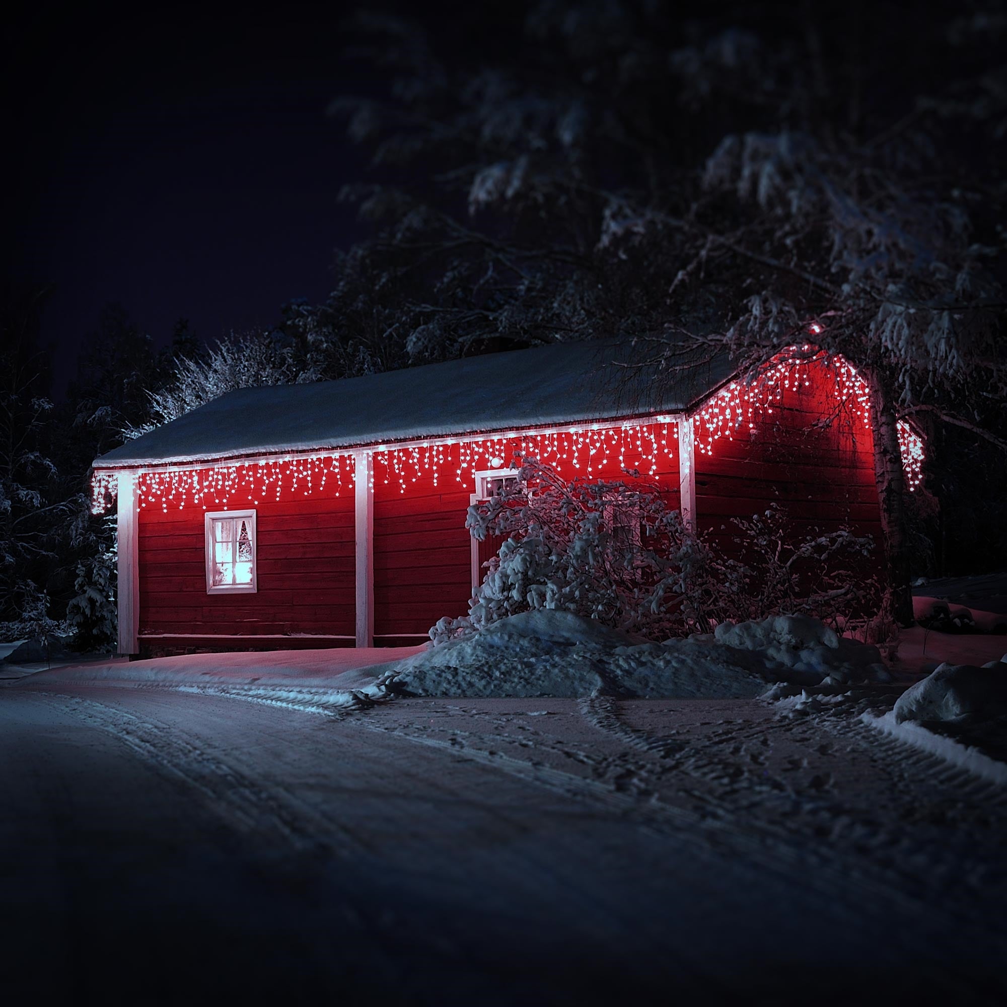 Rotes Haus im Schnee, dekoriert mit roten Lichtern.