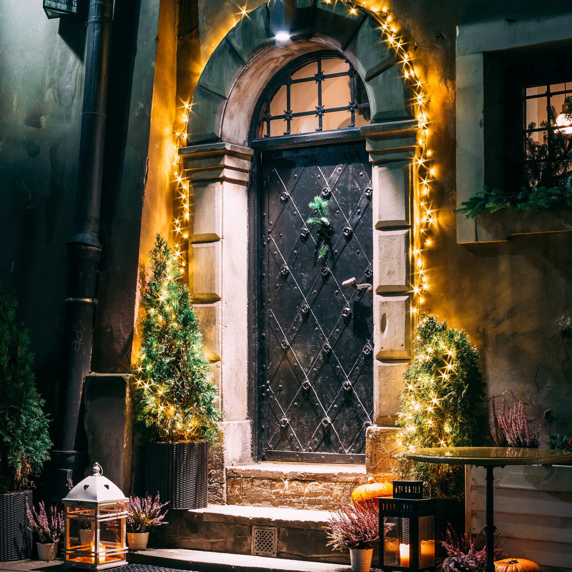 Una puerta decorada festivamente con luces y plantas.