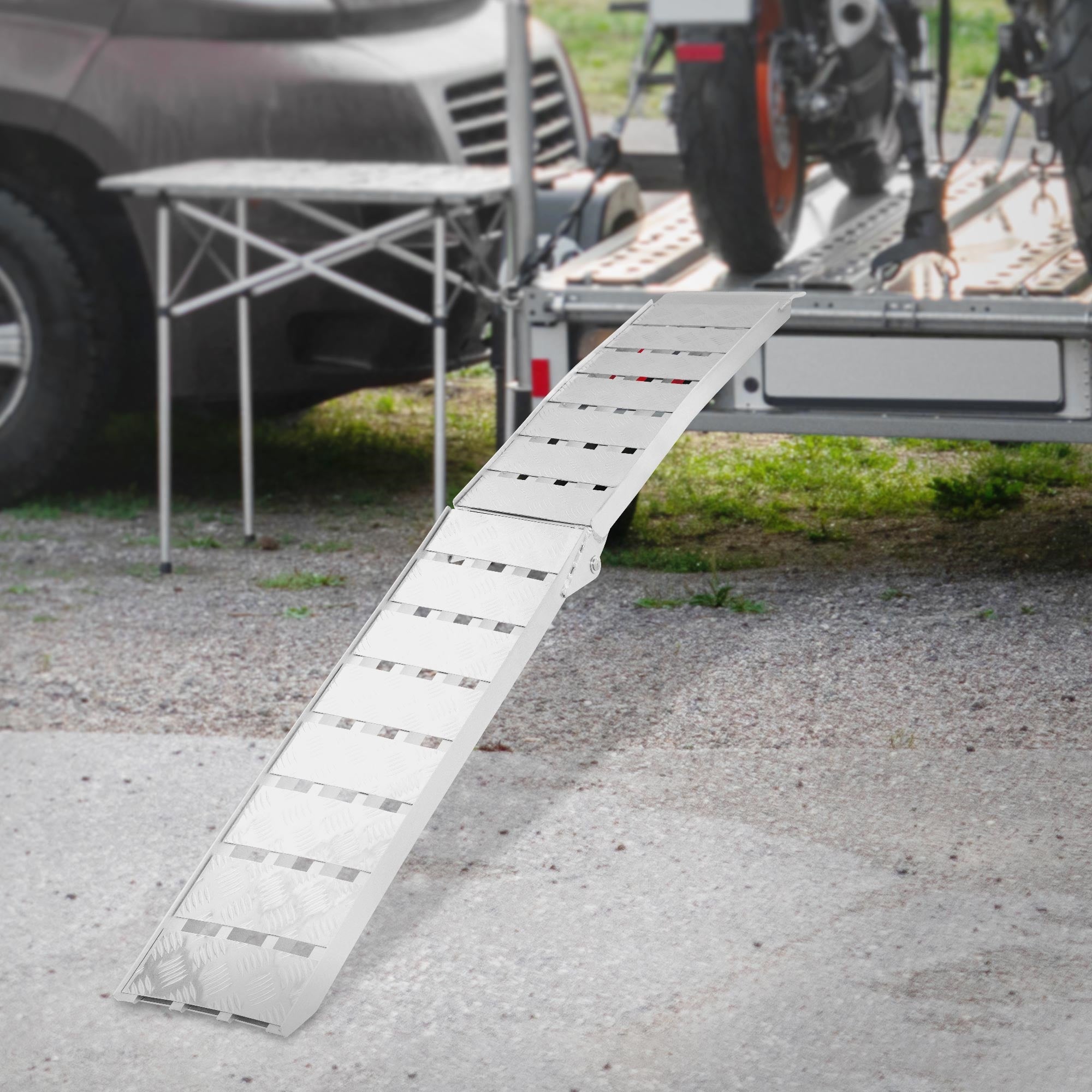 Eine Rampe aus Metall, die zu einem Anhänger führt, mit einem Tisch im Hintergrund.