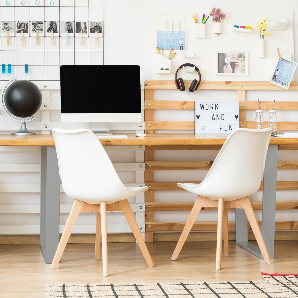 Un bureau avec un ordinateur, deux chaises et une décoration au mur.