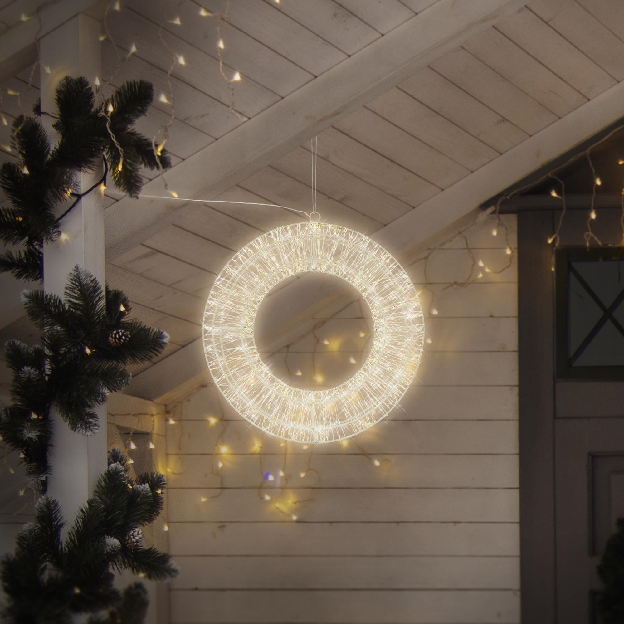 Gloeiende, ronde lichtkrans hangt in een kamer met kerstdecoratie.