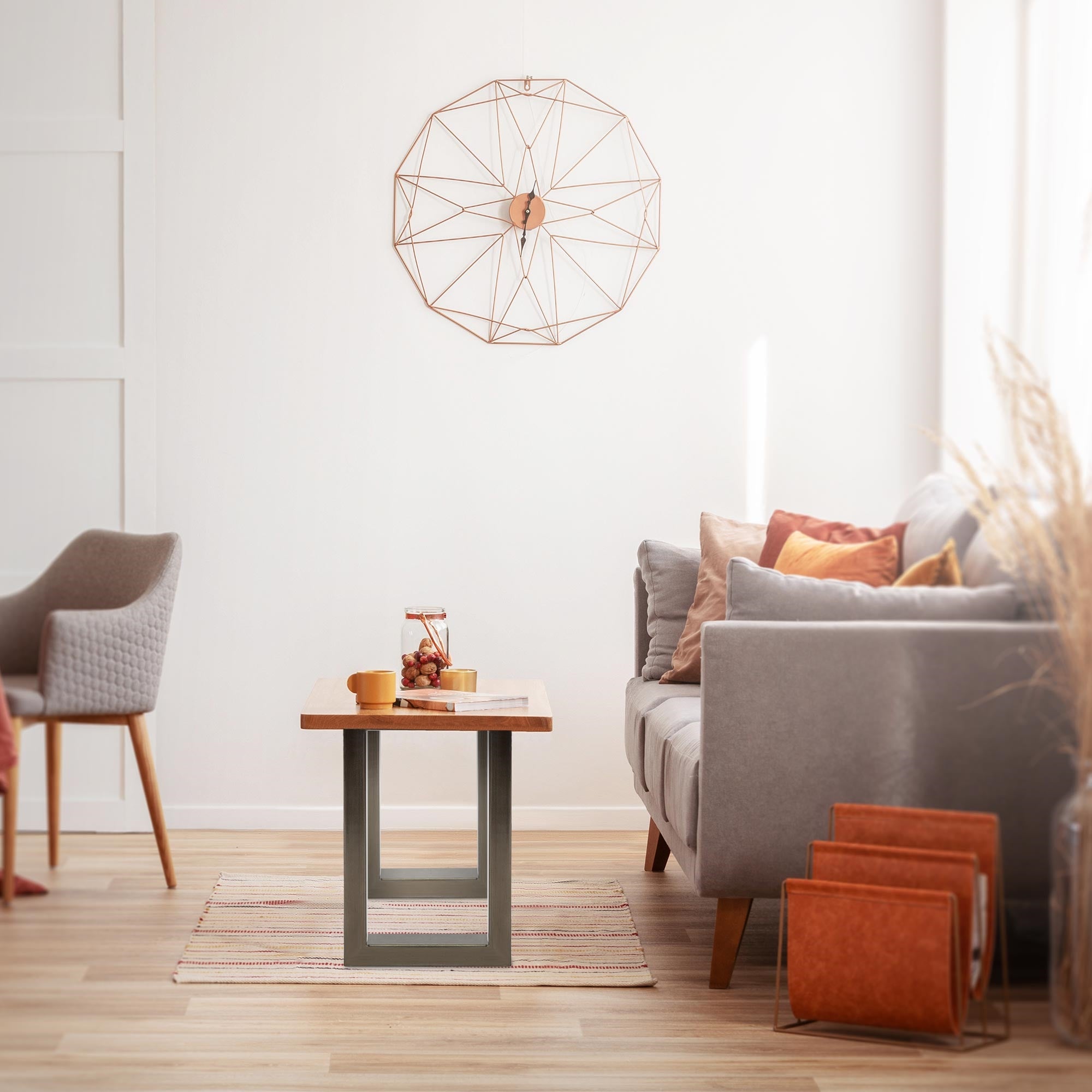 Wohnzimmer mit grauem Sofa, Tisch und Wanddekoration in Form eines großen Rades.
