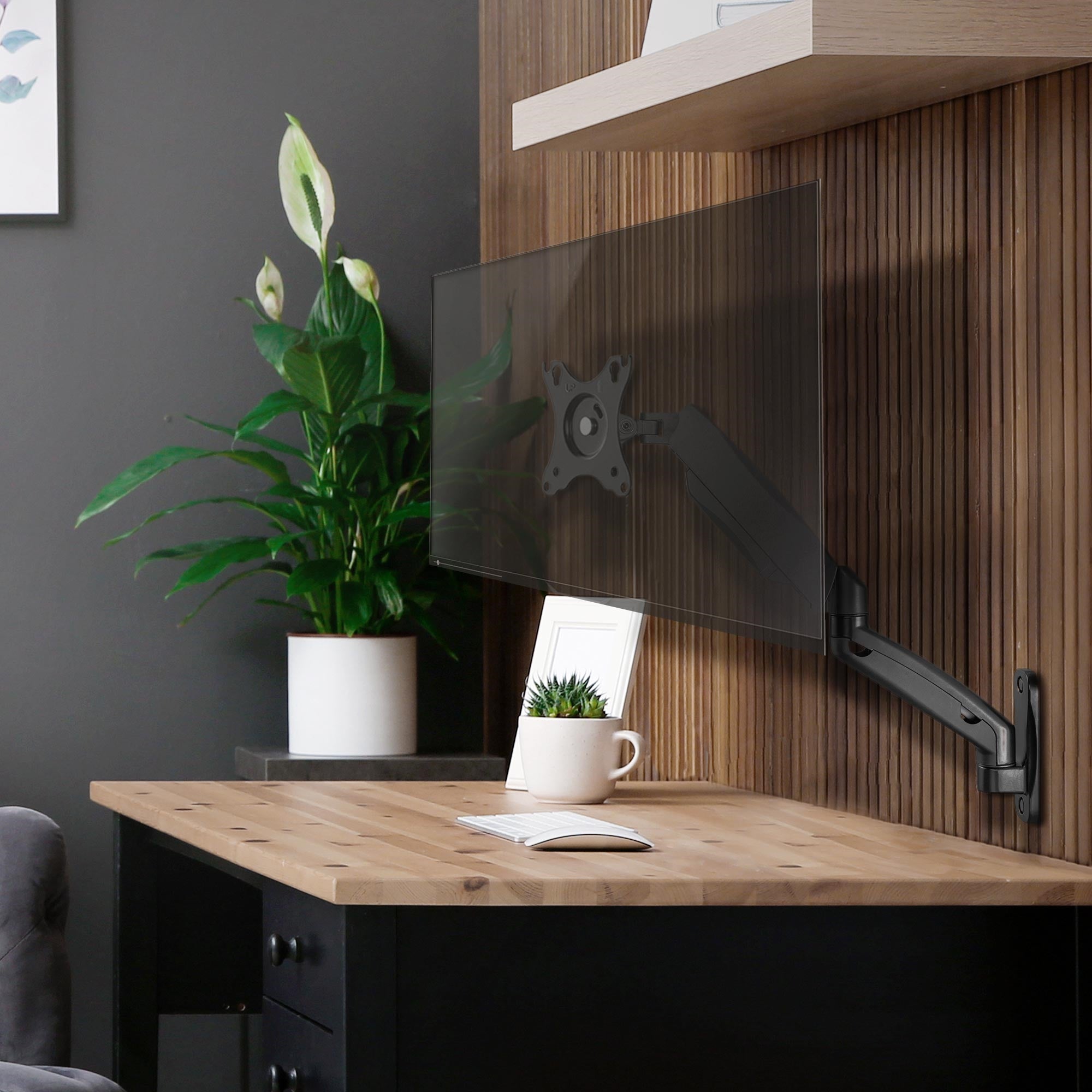 Wandmontierter Monitorarm an einem Holzregal mit Pflanze und Schreibtisch.
