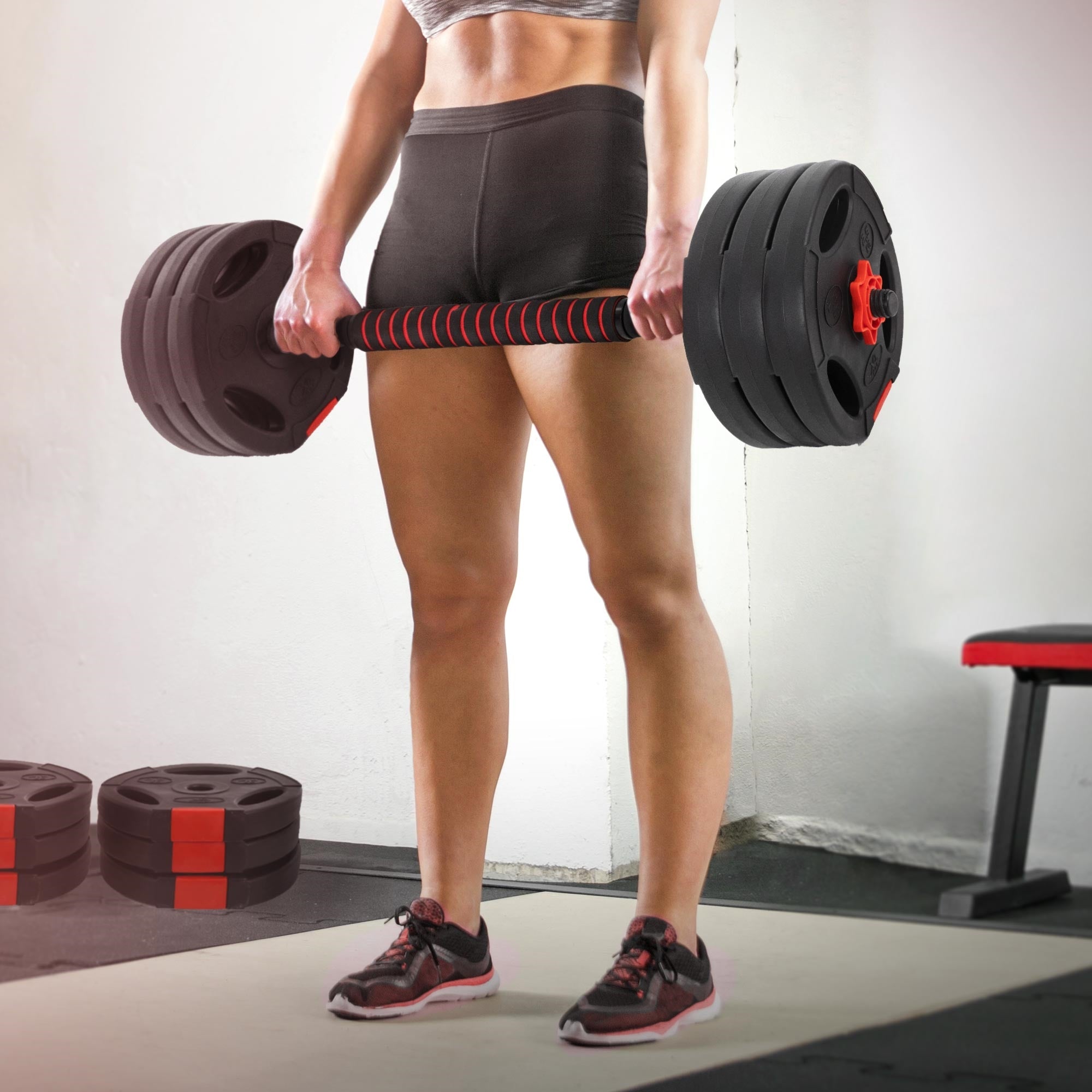 Osoba zvedá těžkou činku s váhami ve fitness centru.