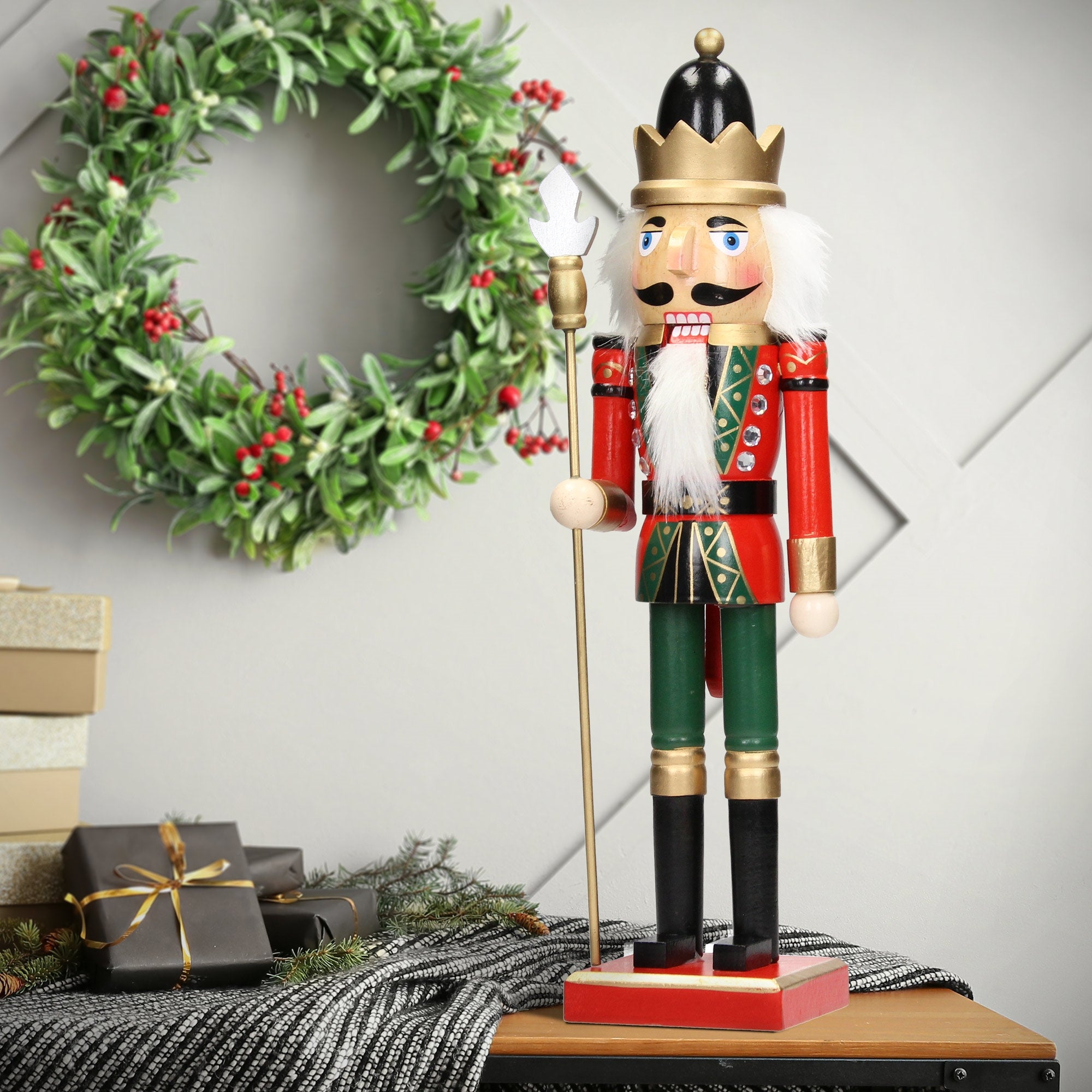 Nutcracker with crown, standing in front of a Christmas wreath.