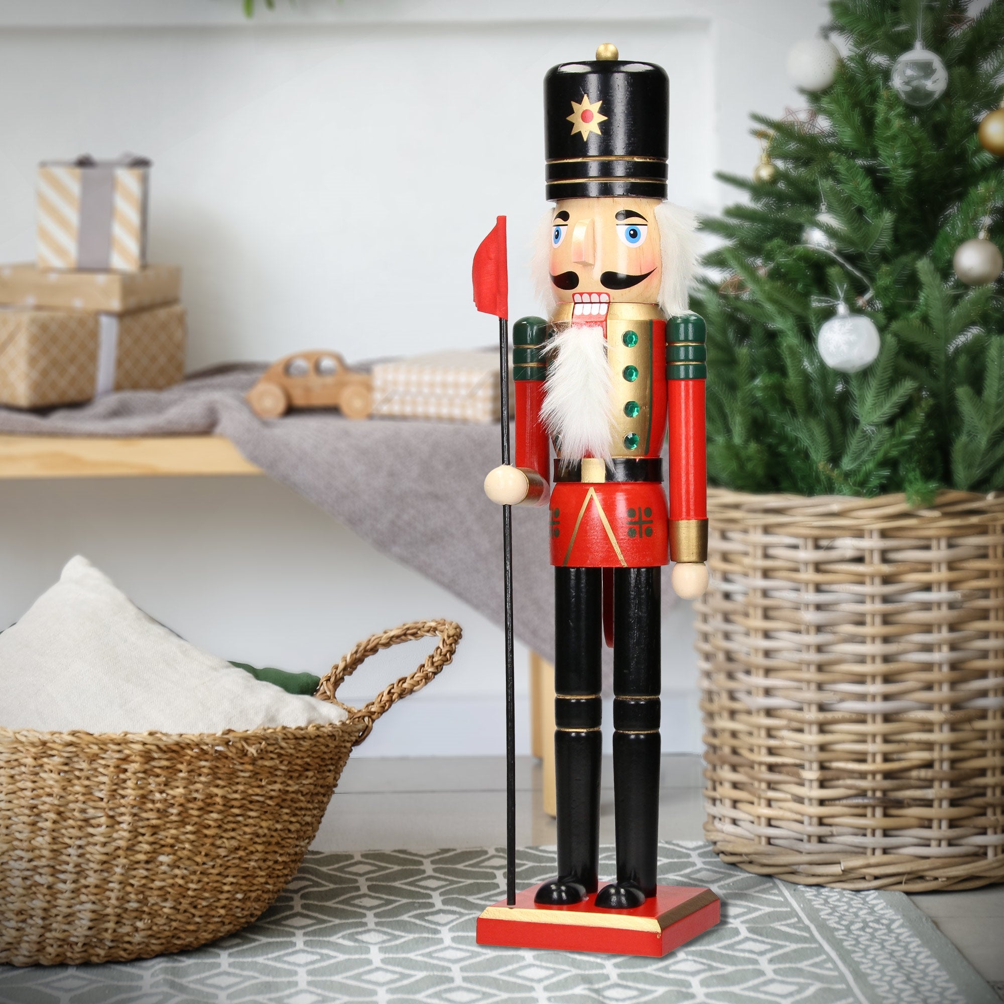 Nutcracker standing next to a Christmas tree and gifts.