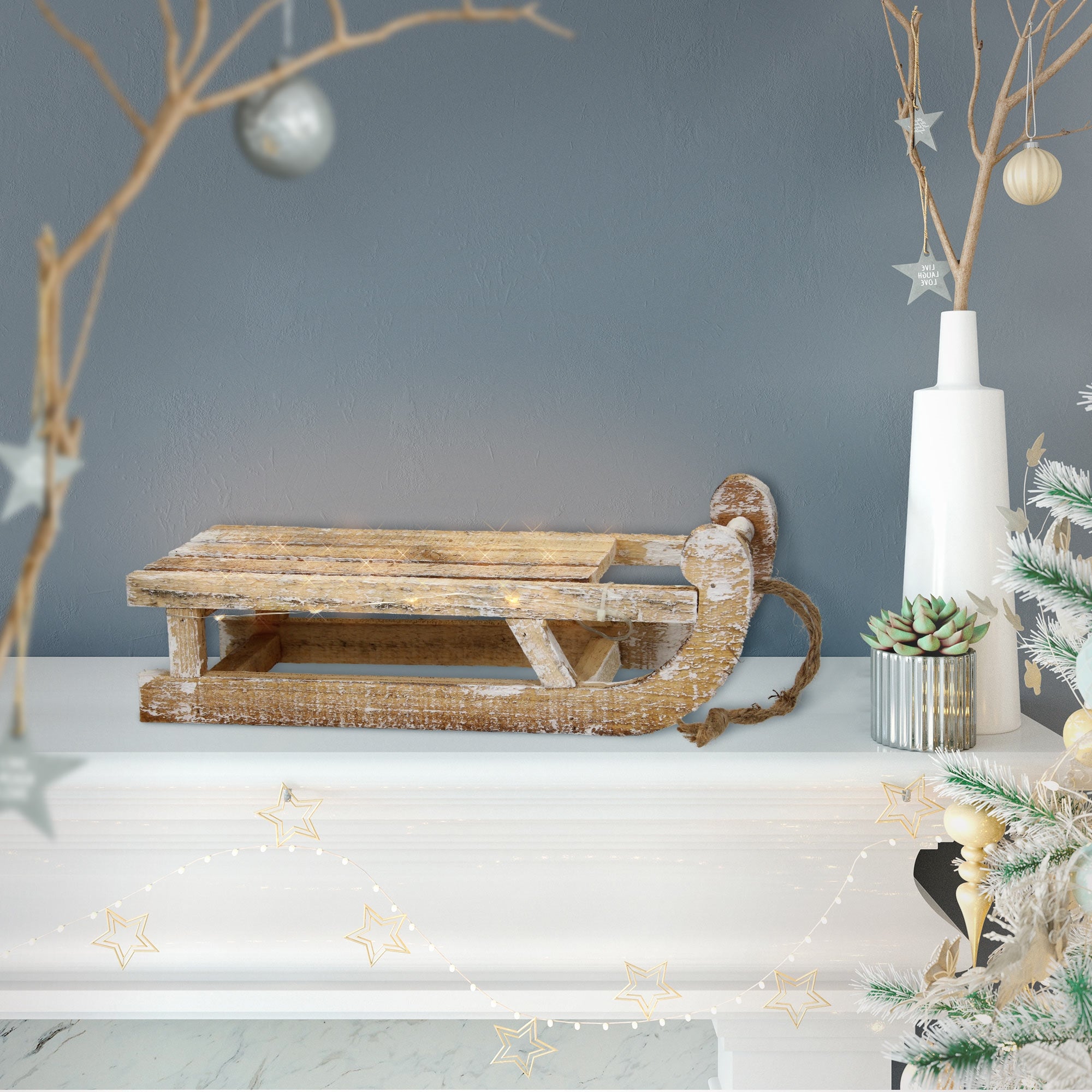Ein Holzschlitten auf einem Tisch, umgeben von Weihnachtsdekoration.