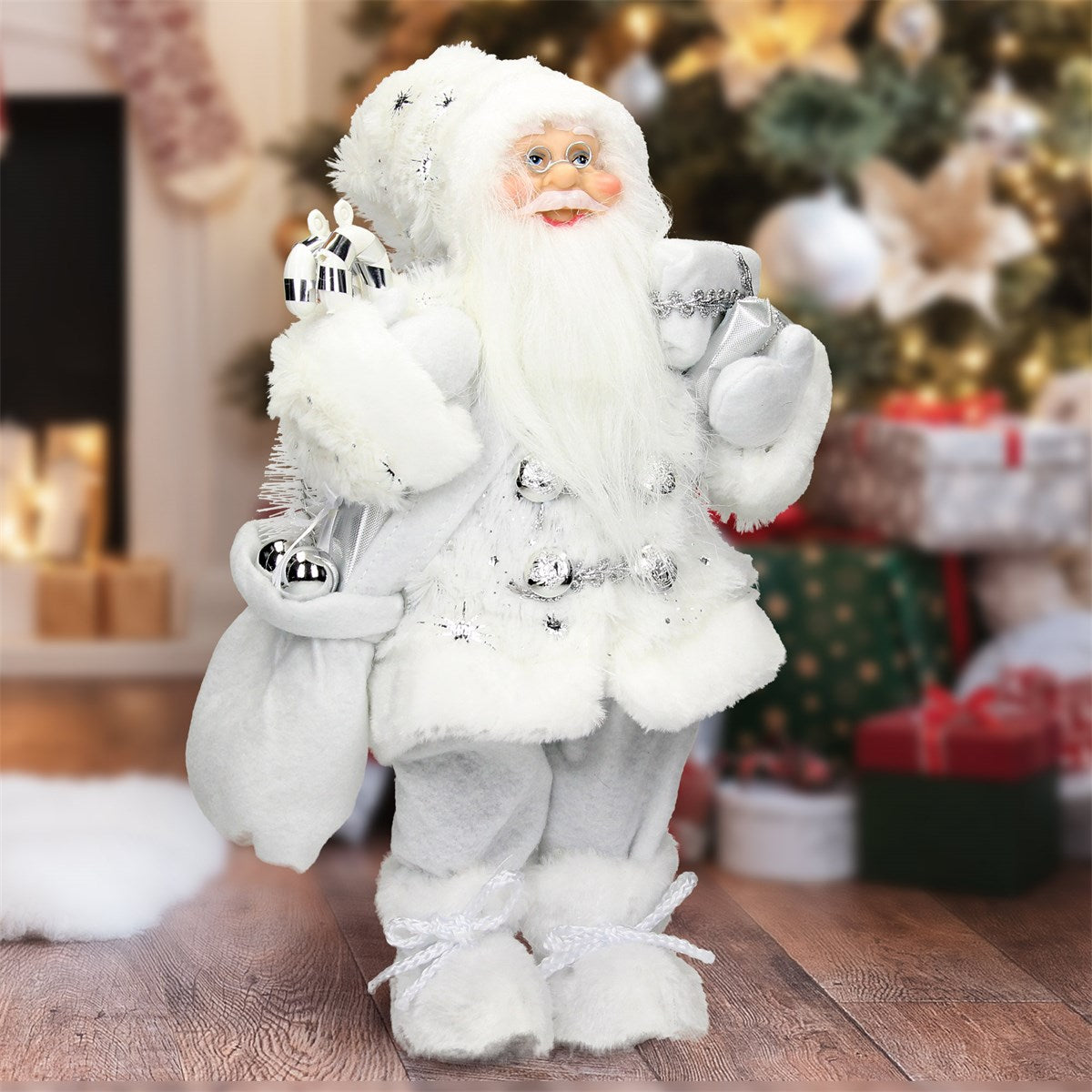 Santa Claus v bílém rouchu s dárky před vánočním stromkem.