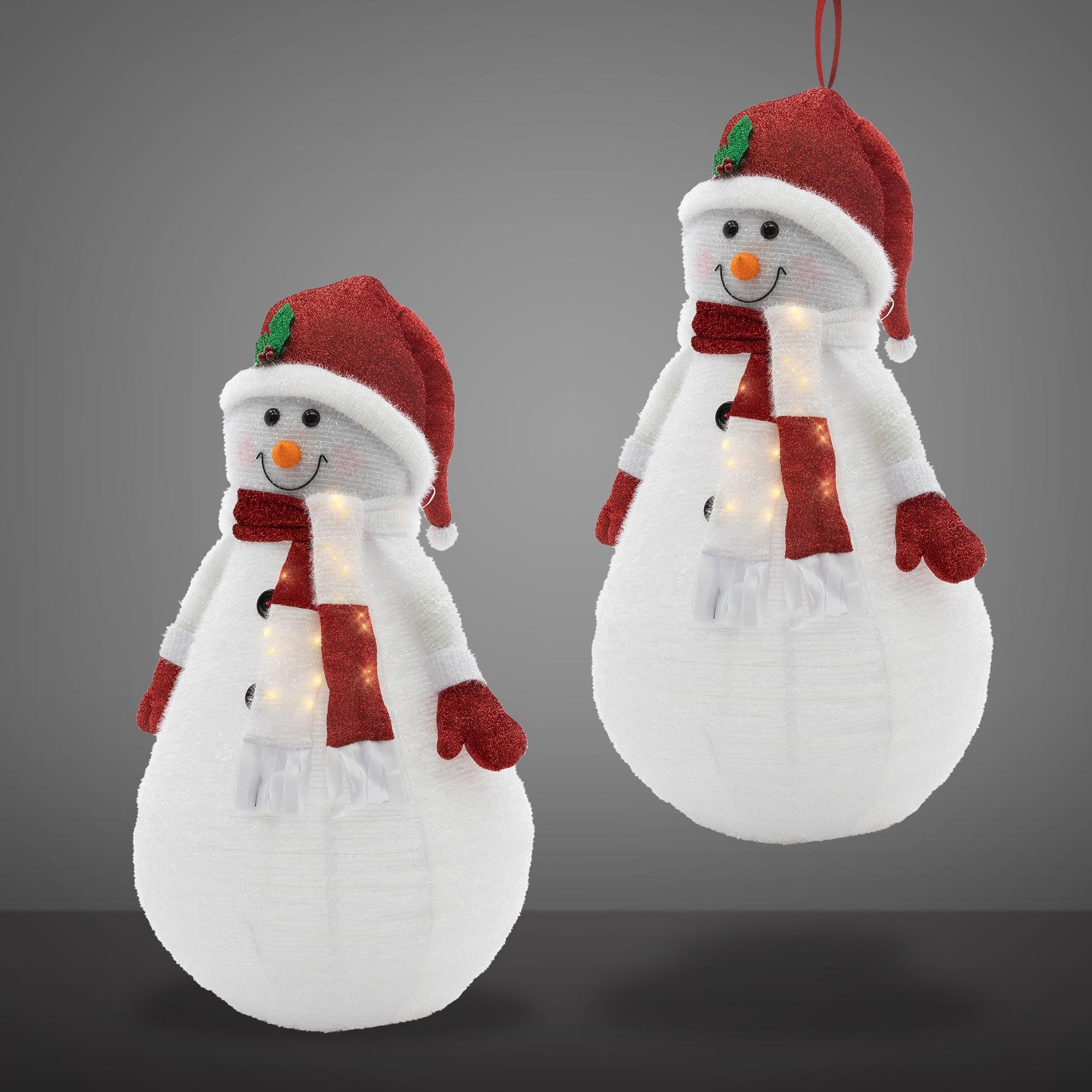 Zwei leuchtende Schneemann-Dekorationen mit roten Hüten und Schals auf grauem Hintergrund.