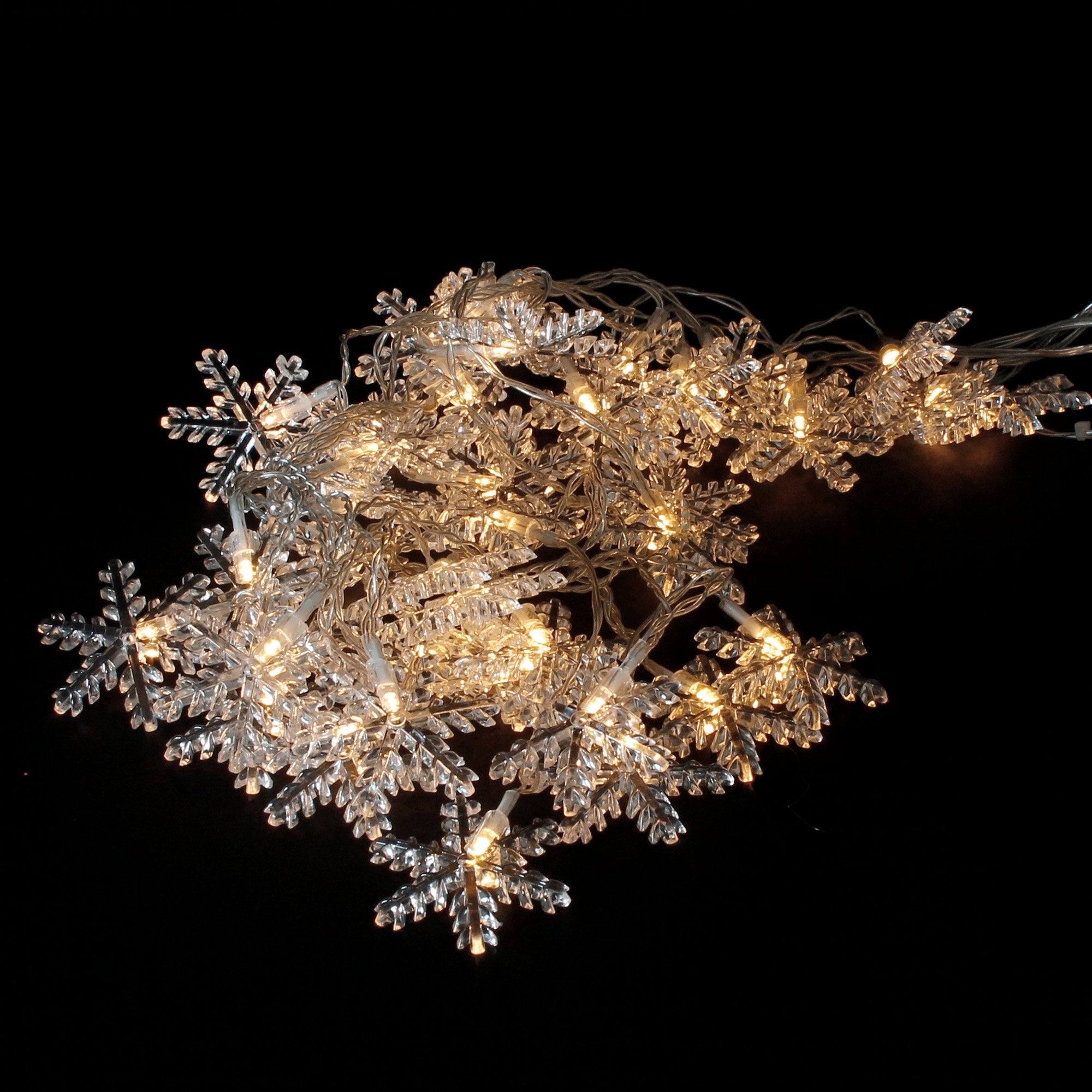 Catena luminosa con luci a forma di fiocco di neve su sfondo nero.