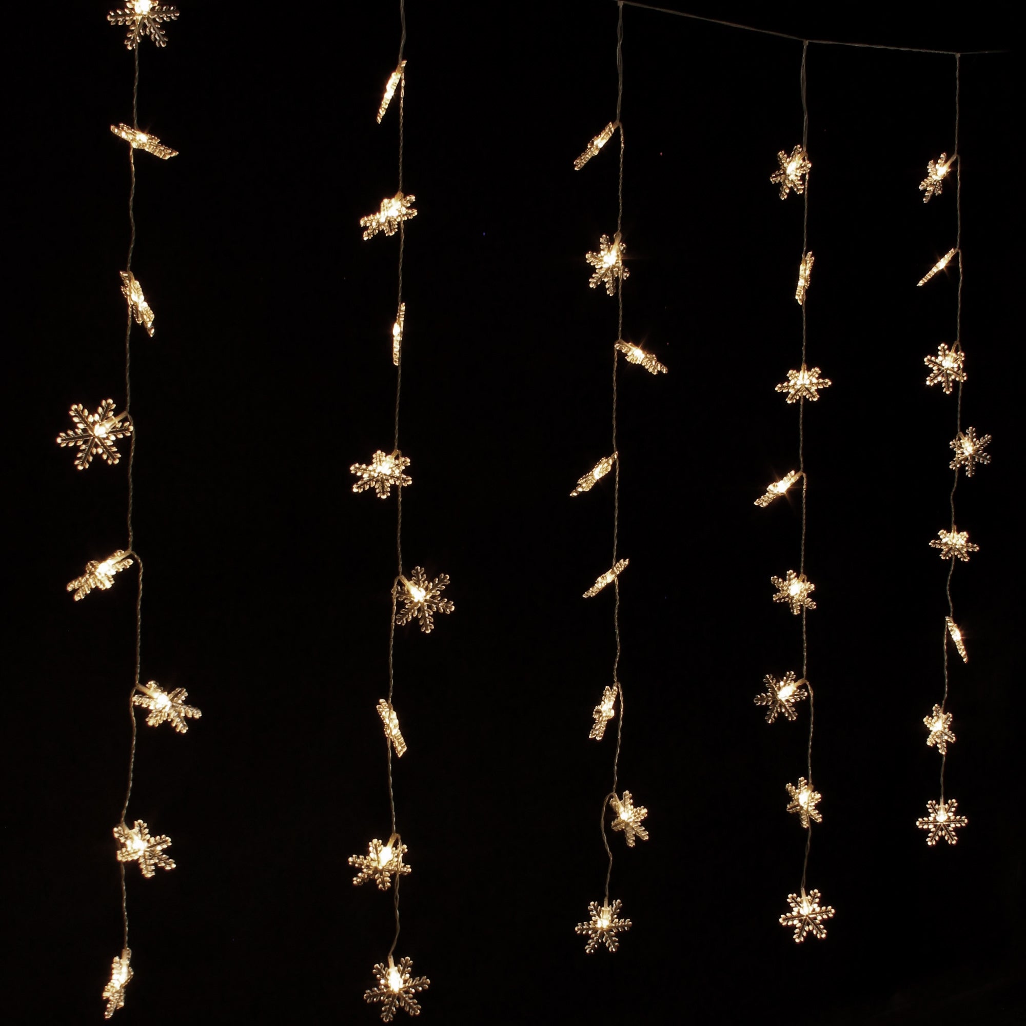 Tenda luminosa con luci a forma di fiocco di neve su sfondo nero.