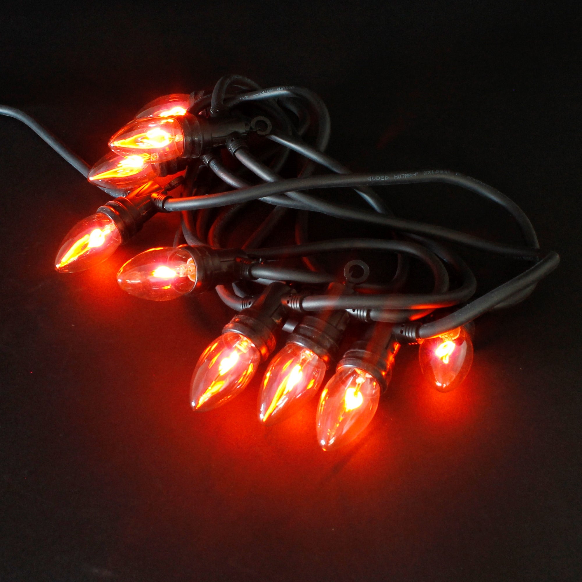 Cadena de luces con lámparas naranjas sobre un fondo negro.