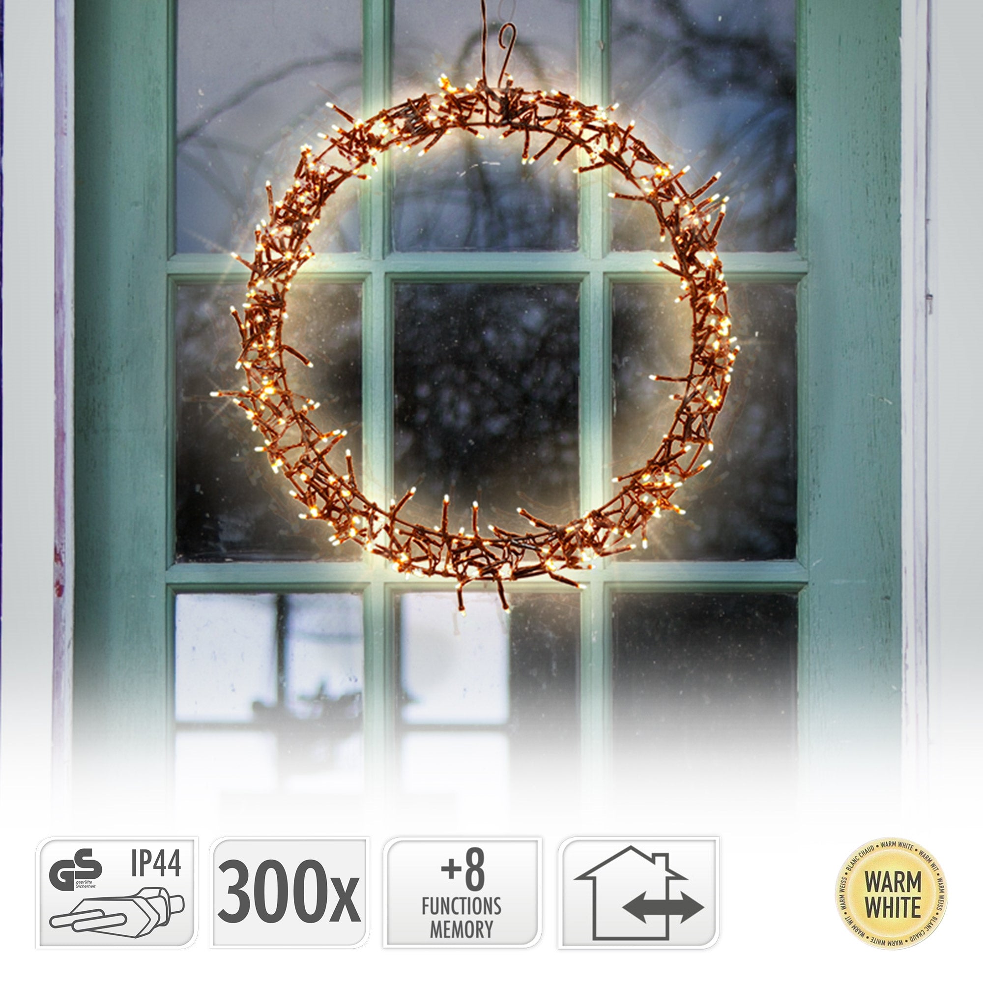 Ein runder Kranz aus Zweigen mit warmweißen Lichtern, hängt vor einem Fenster.