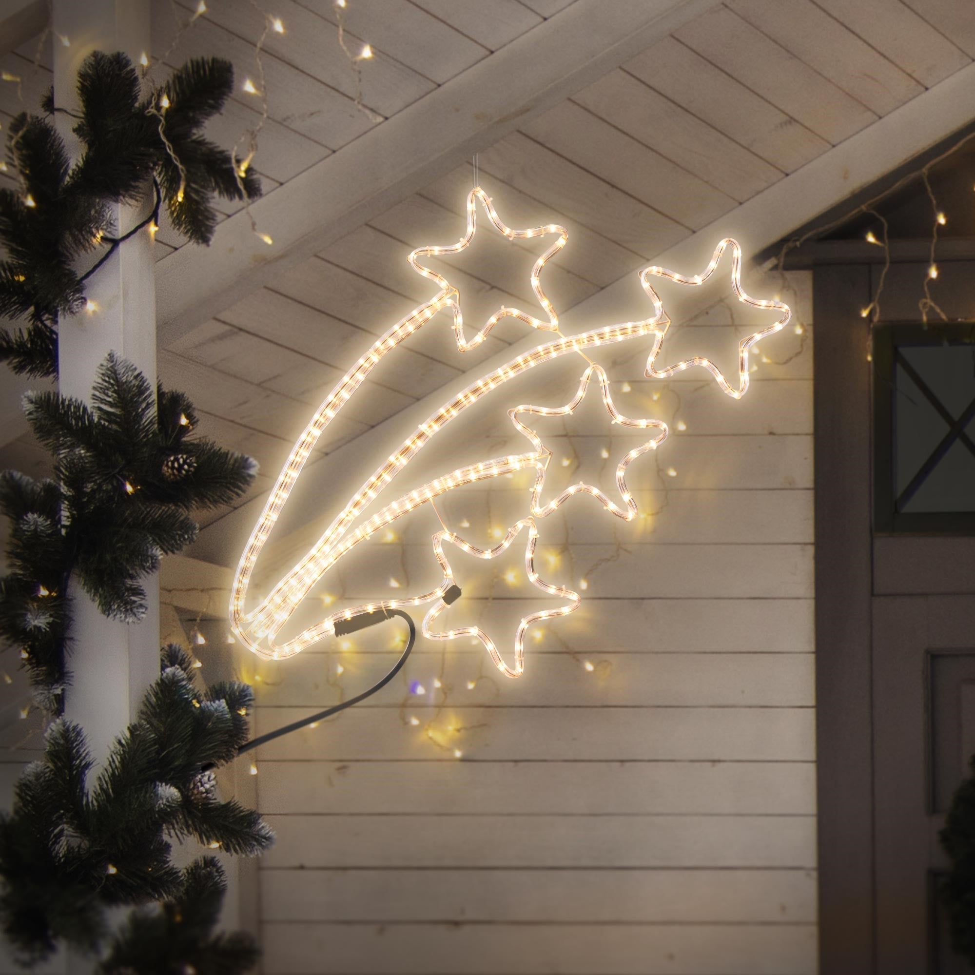 Beleuchtete Sternlichterkette an einer Wand mit Weihnachtsdekoration.