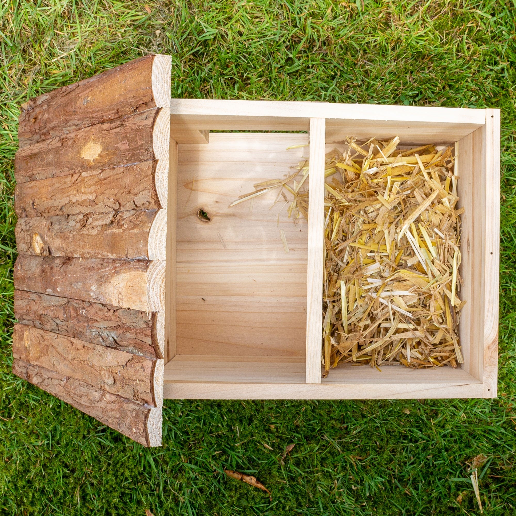 Ein offenes Holzbehälter mit Stroh und einer Trennwand in der Mitte.