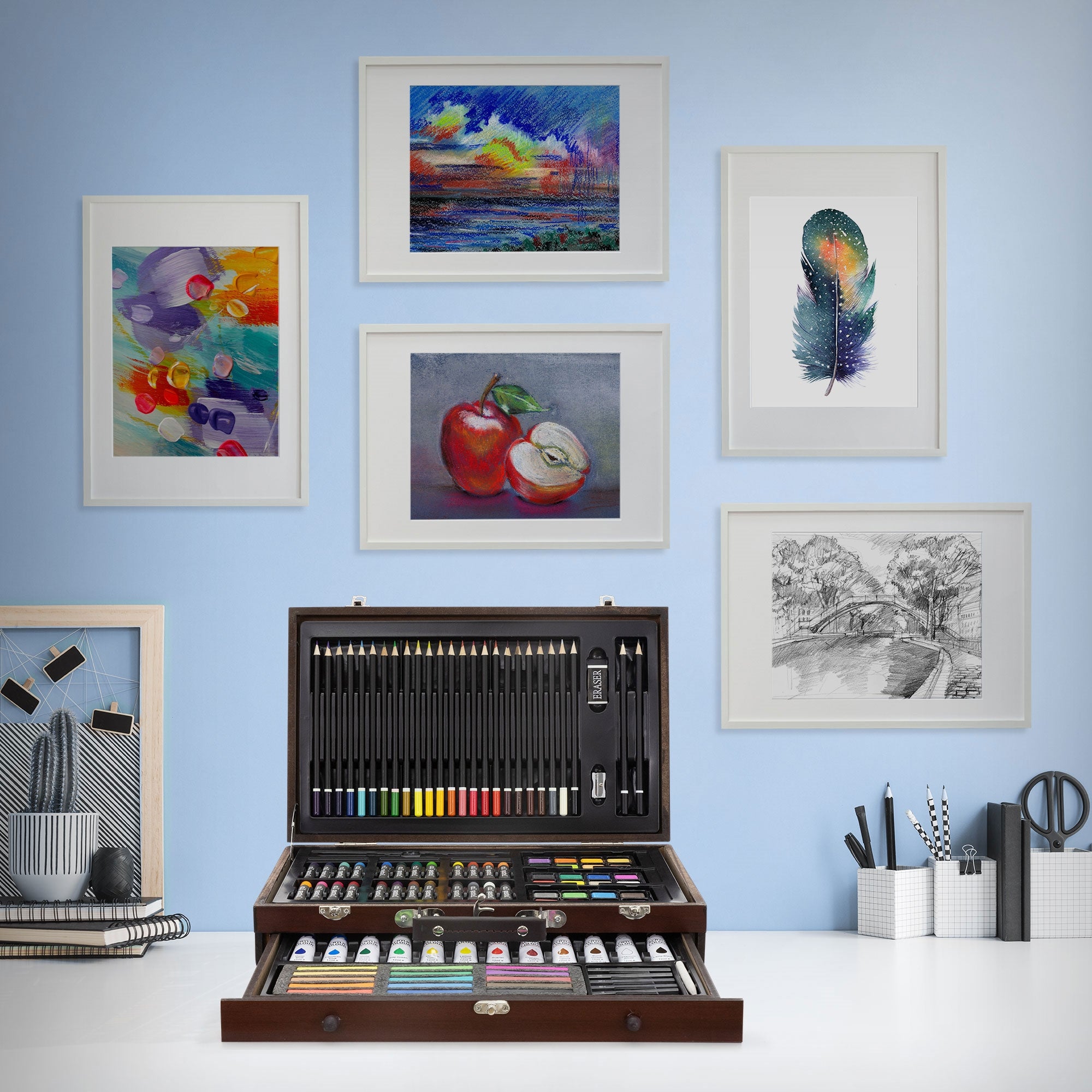 Art set with colors and pens, surrounded by framed pictures on a wall.