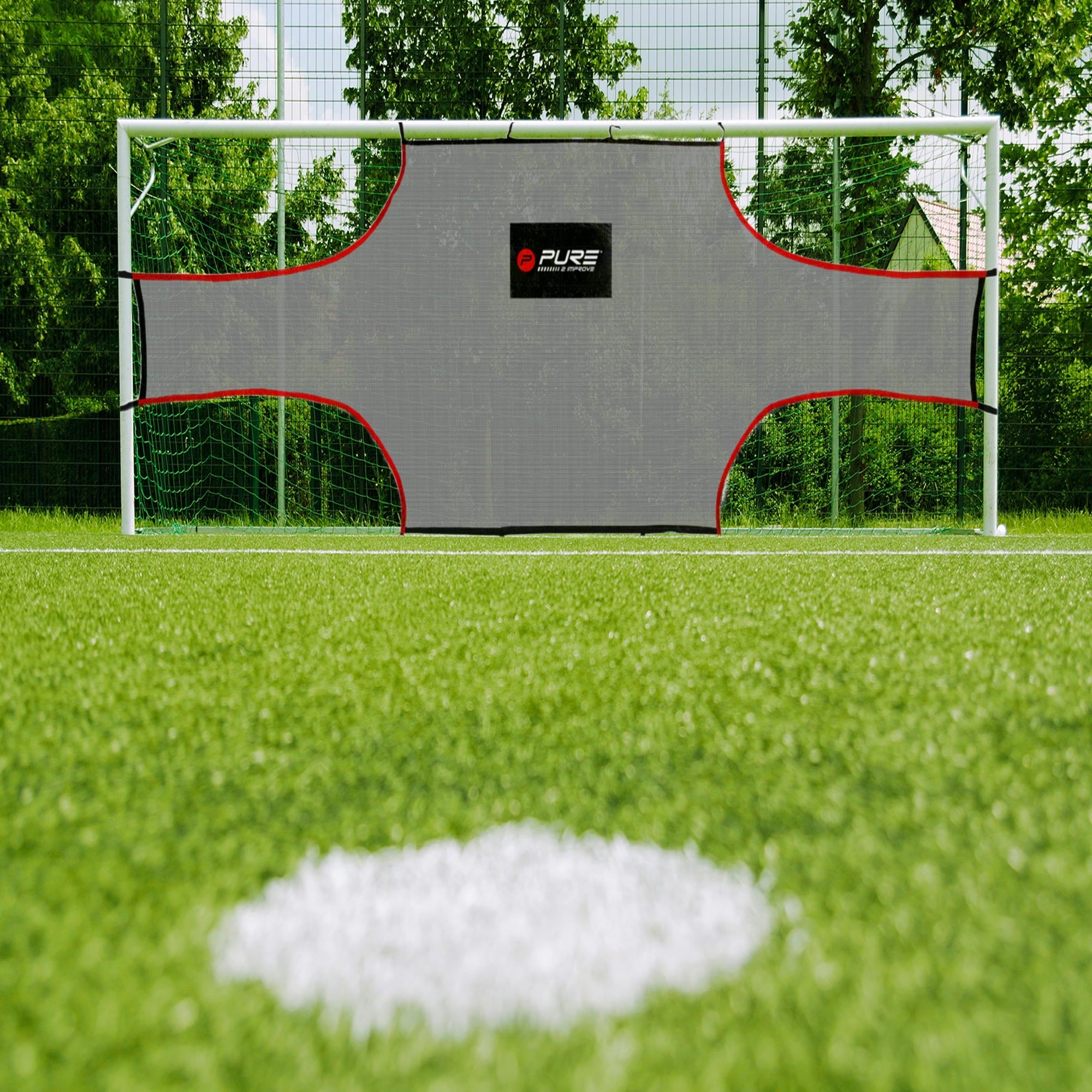 Fodboldmål med et gråt net og rød kant på en græsplæne.