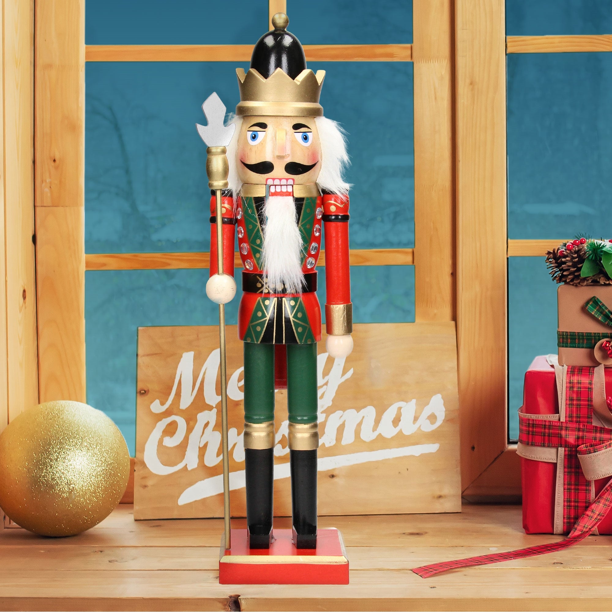 Nussknackerfigur mit Krone, rotem und grünem Anzug vor einem Fenster mit Weihnachtsdeko.