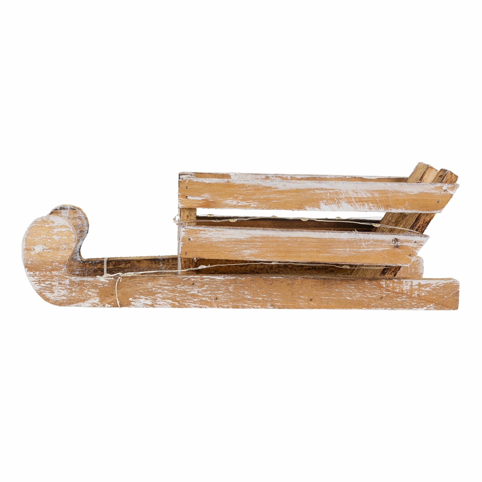 Un trineo de madera visto de lado, ligeramente desgastado y pintado de blanco.