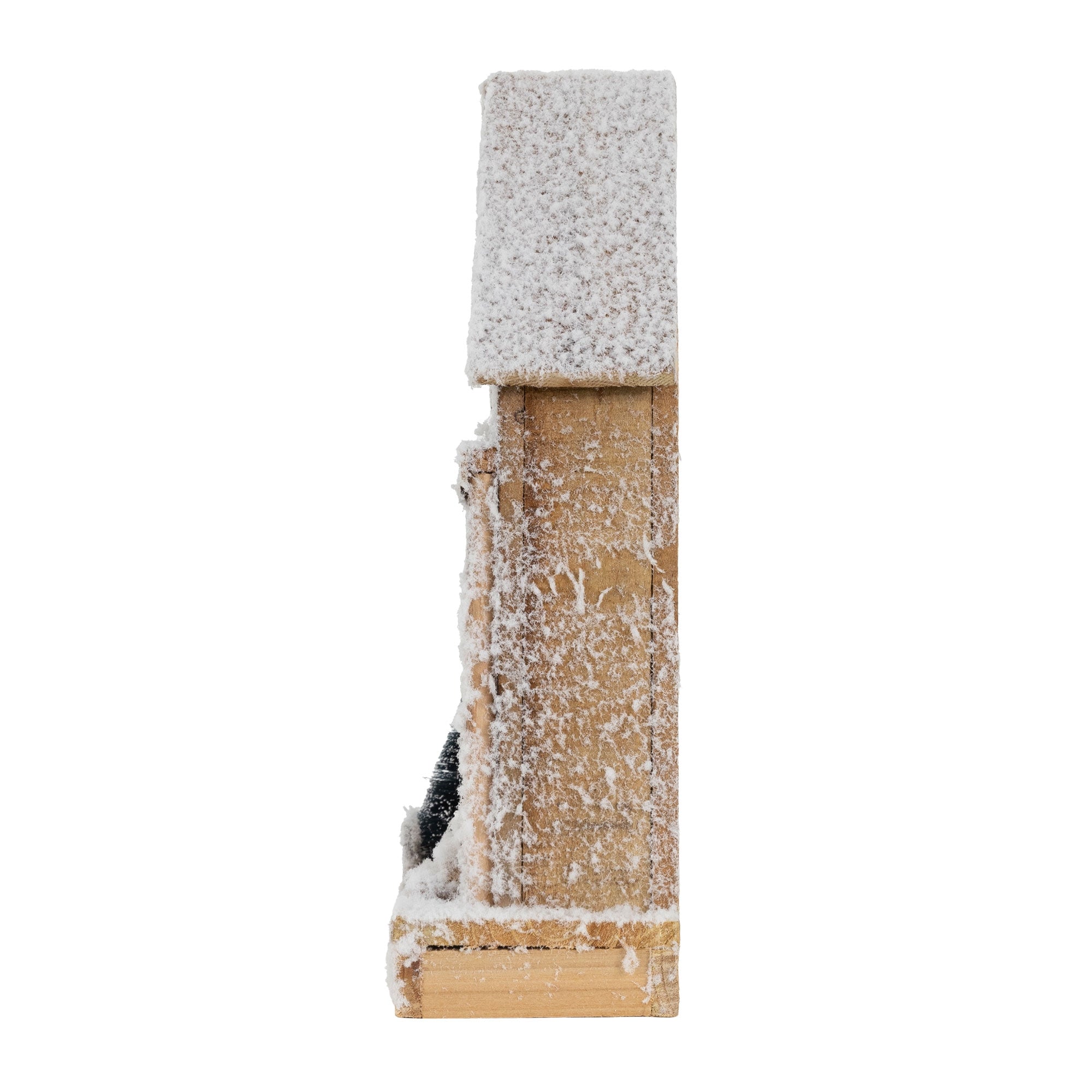 Seitenansicht eines Holzhauses mit Schnee und Weihnachtsbaum.