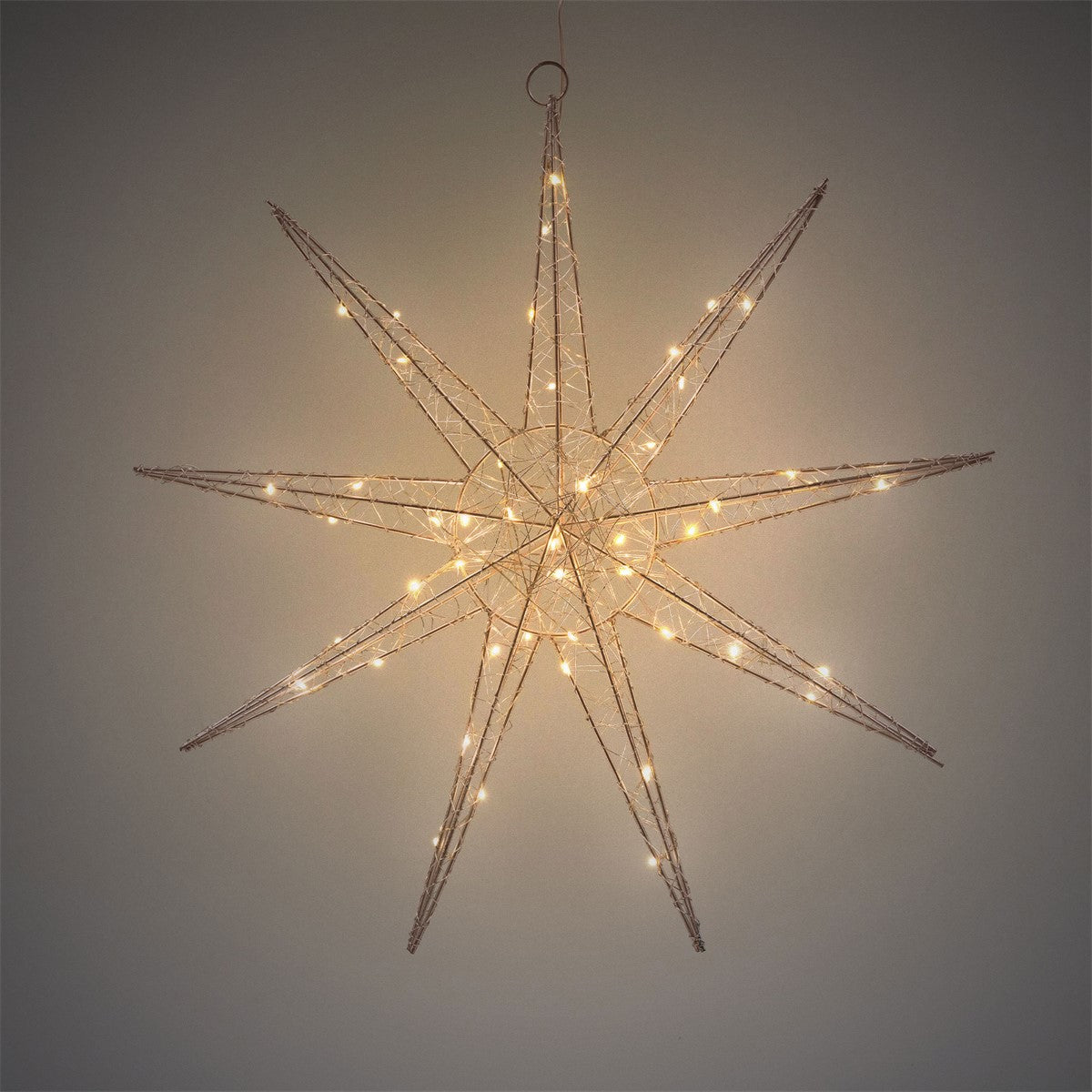 Una grande stella luminosa in filo metallico è appesa a una parete.