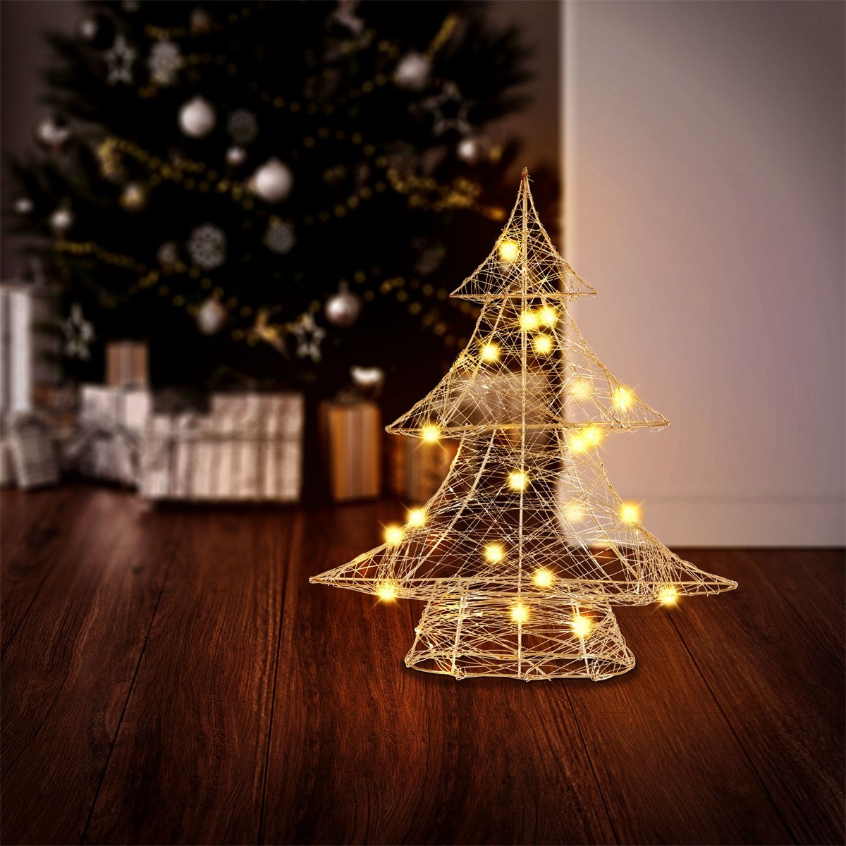 An illuminated Christmas tree in front of a Christmas tree in the background.