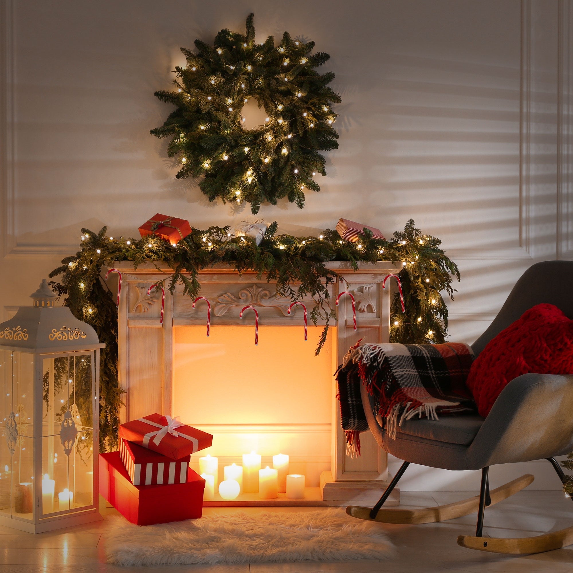 Egy ünnepélyesen díszített kandalló ajándékokkal és gyertyákkal.