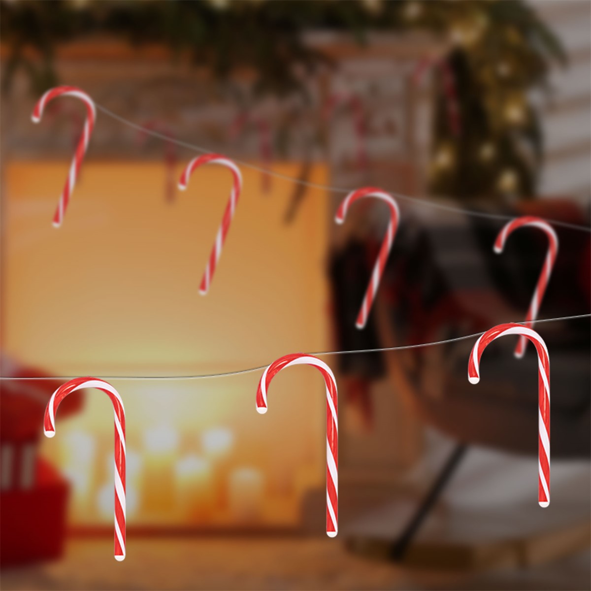 Sechs rot-weiß gestreifte Zuckerstangen hängen an Schnüren vor unscharfem Hintergrund.