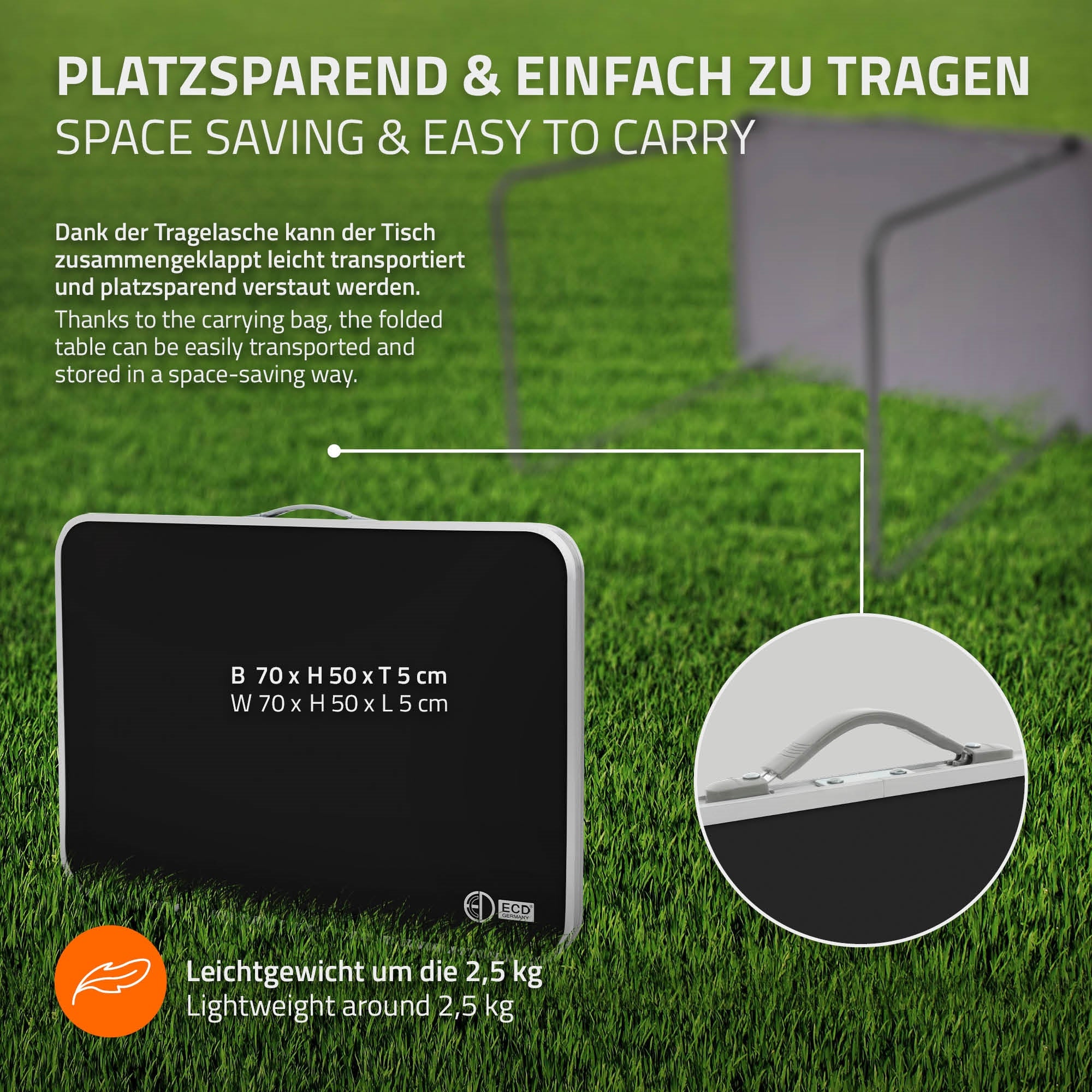 Klappbarer Tisch in schwarzer Farbe, zusammengeklappt und mit Tragelasche auf grünem Rasen.