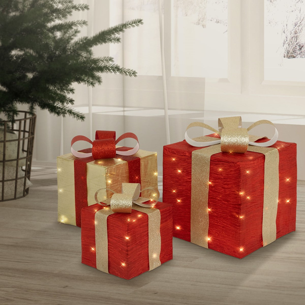 Drei rot-goldene Geschenkboxen mit Schleifen und leuchtenden Punkten stehen neben einem Tannenbaum.