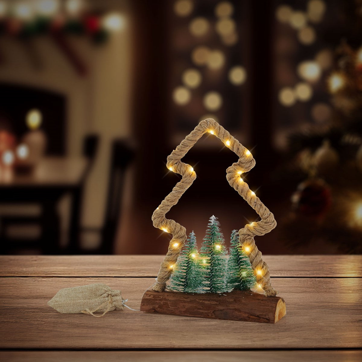 Decoratie van groene borstelboompjes op een houten voet, omlijst door een verlicht touw in de vorm van een boom.
