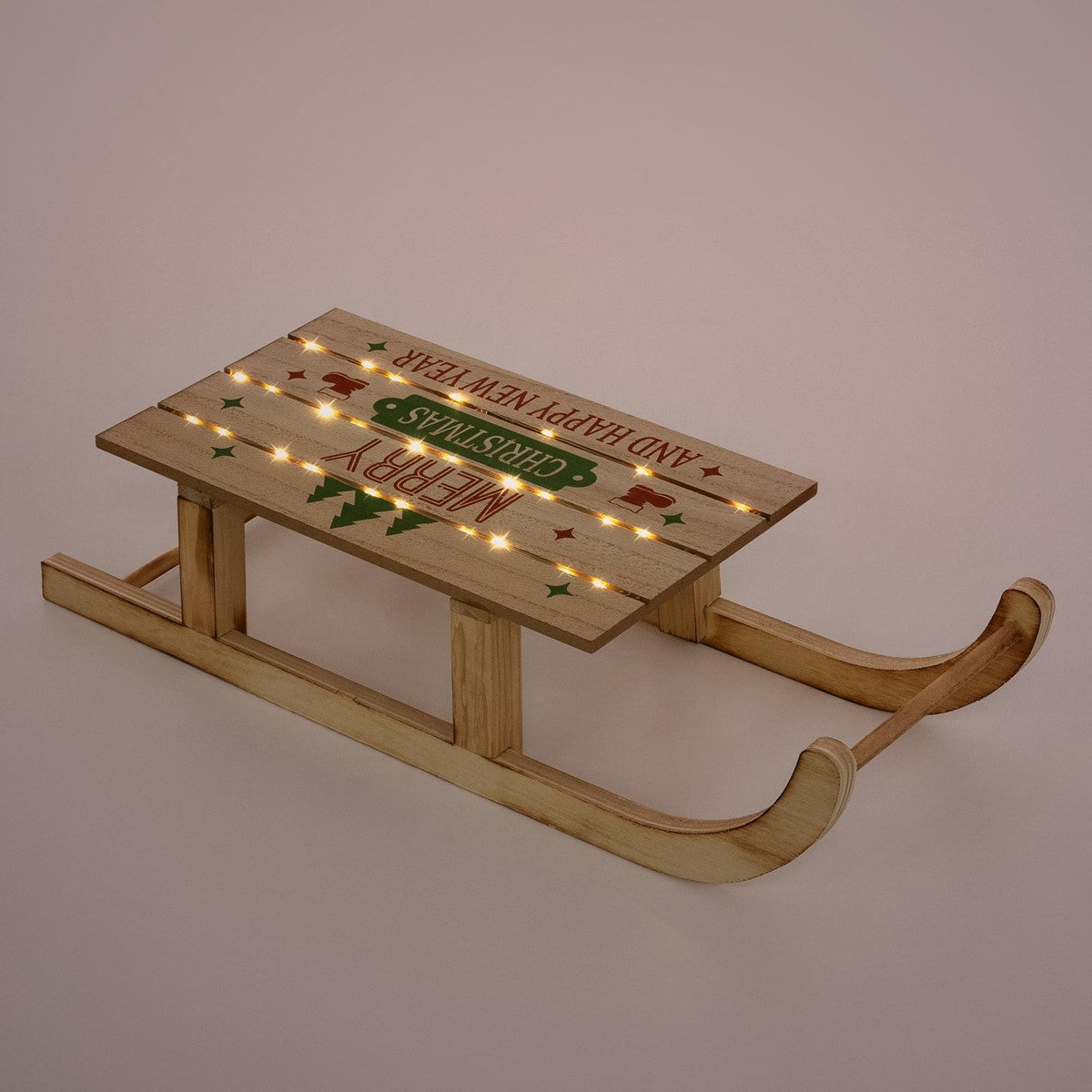 Holzschlitten mit Weihnachtsgrüßen und Lichtern auf einem einfarbigen Hintergrund.