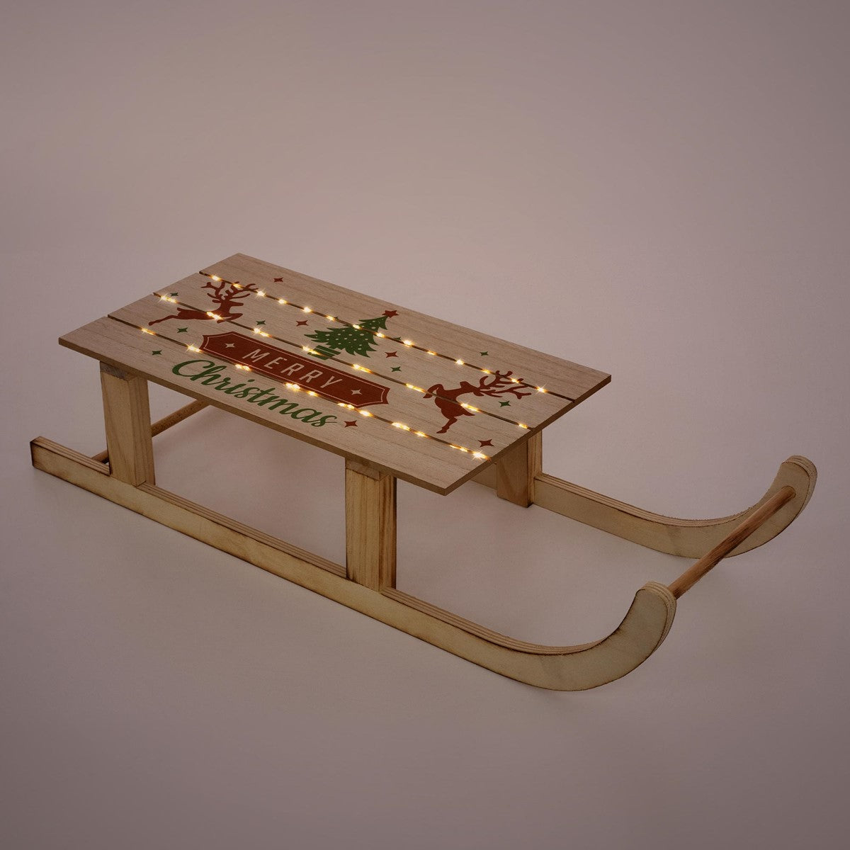 Holzschlitten mit Weihnachtsmotiv und Lichtern auf einem einfarbigen Hintergrund.