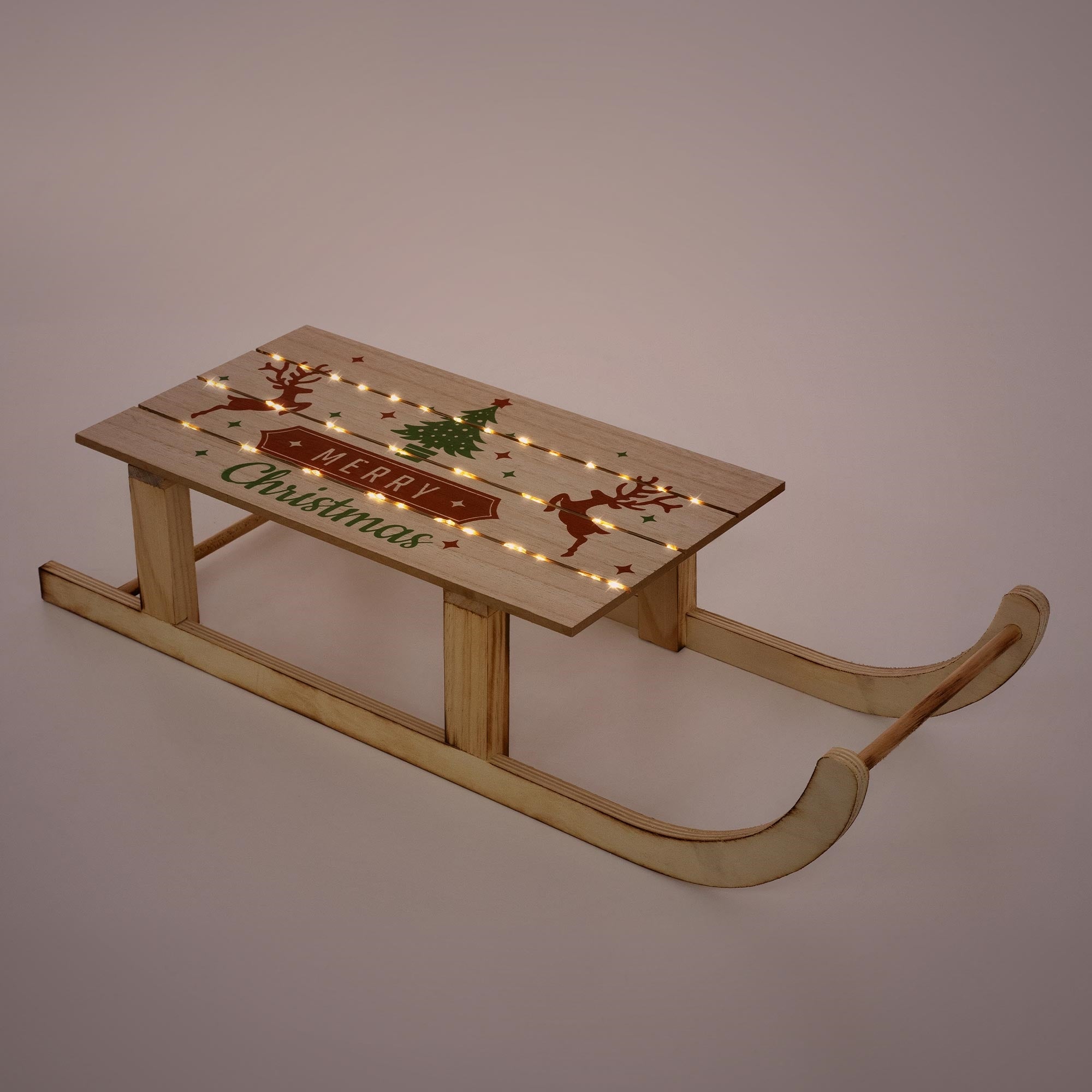Wooden sled with Christmas motif and lights on a solid color background.