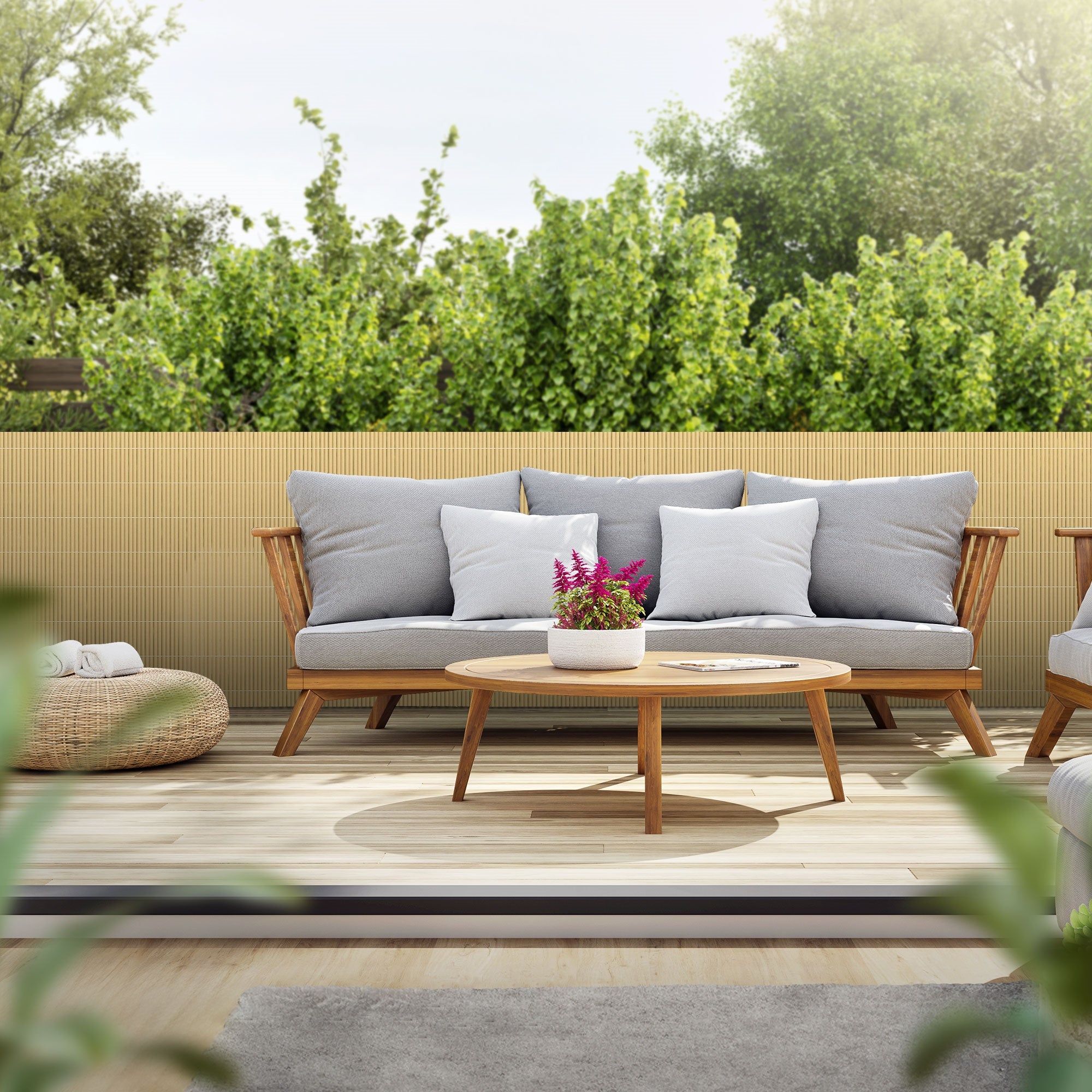 Ein gemütlicher Außenbereich mit Sofa, Tisch und Bambusmatte im Hintergrund.