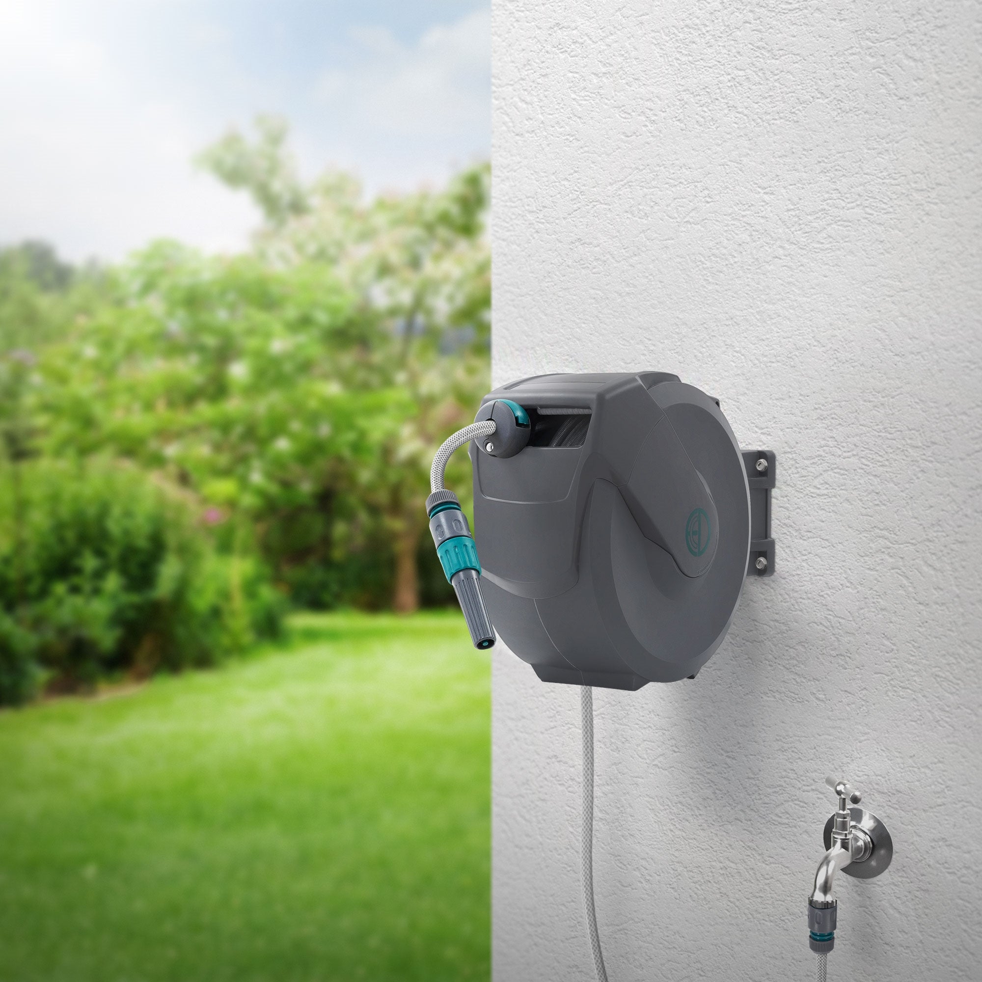 Wasserschlauchaufroller an einer Wand in einem Garten mit grünem Rasen.